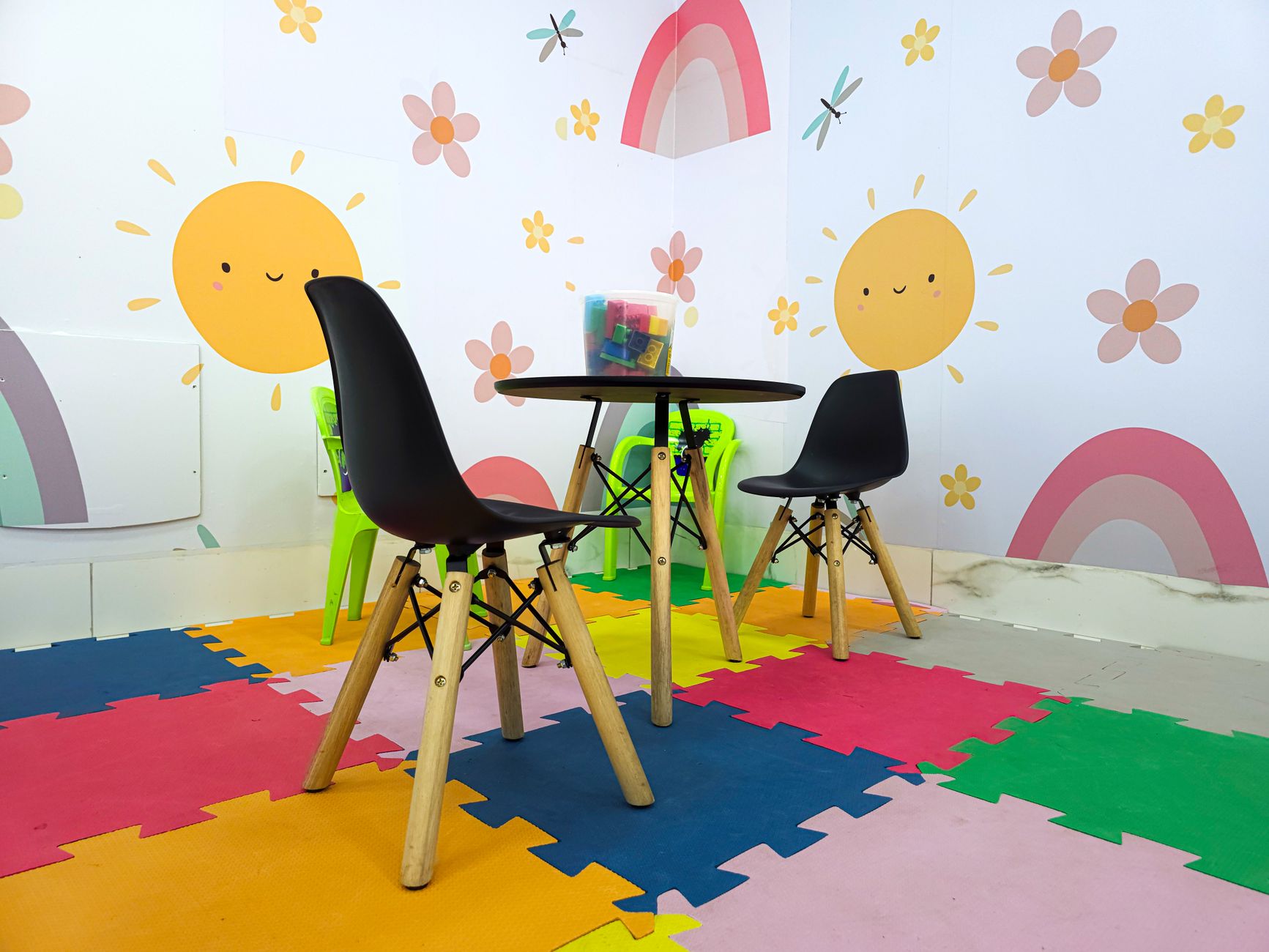 A vibrant waiting area for children featuring colorful flooring, playful wall designs, and a table with toys.