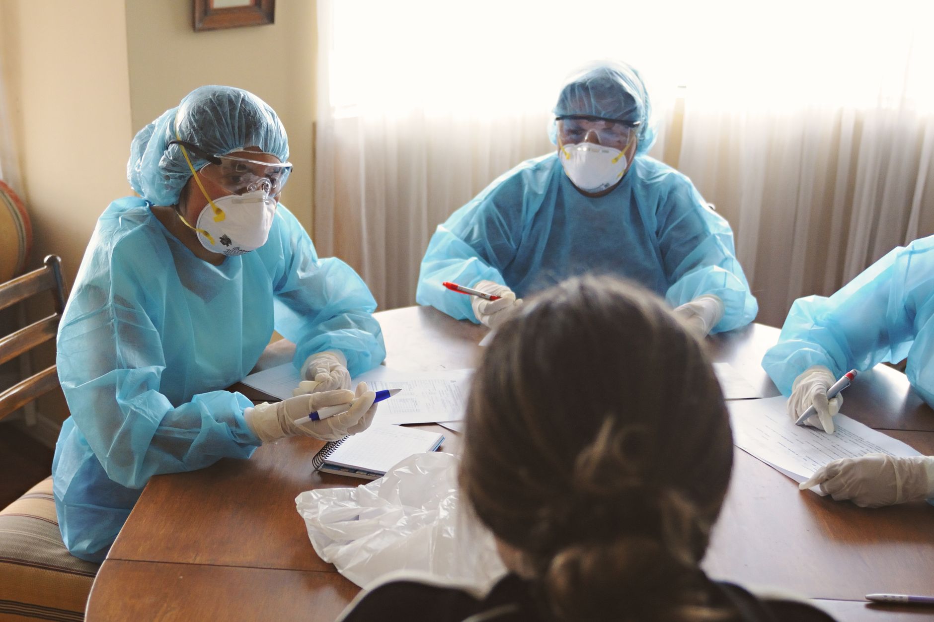 Medical professionals in protective gear discussing treatment plans at a table.
