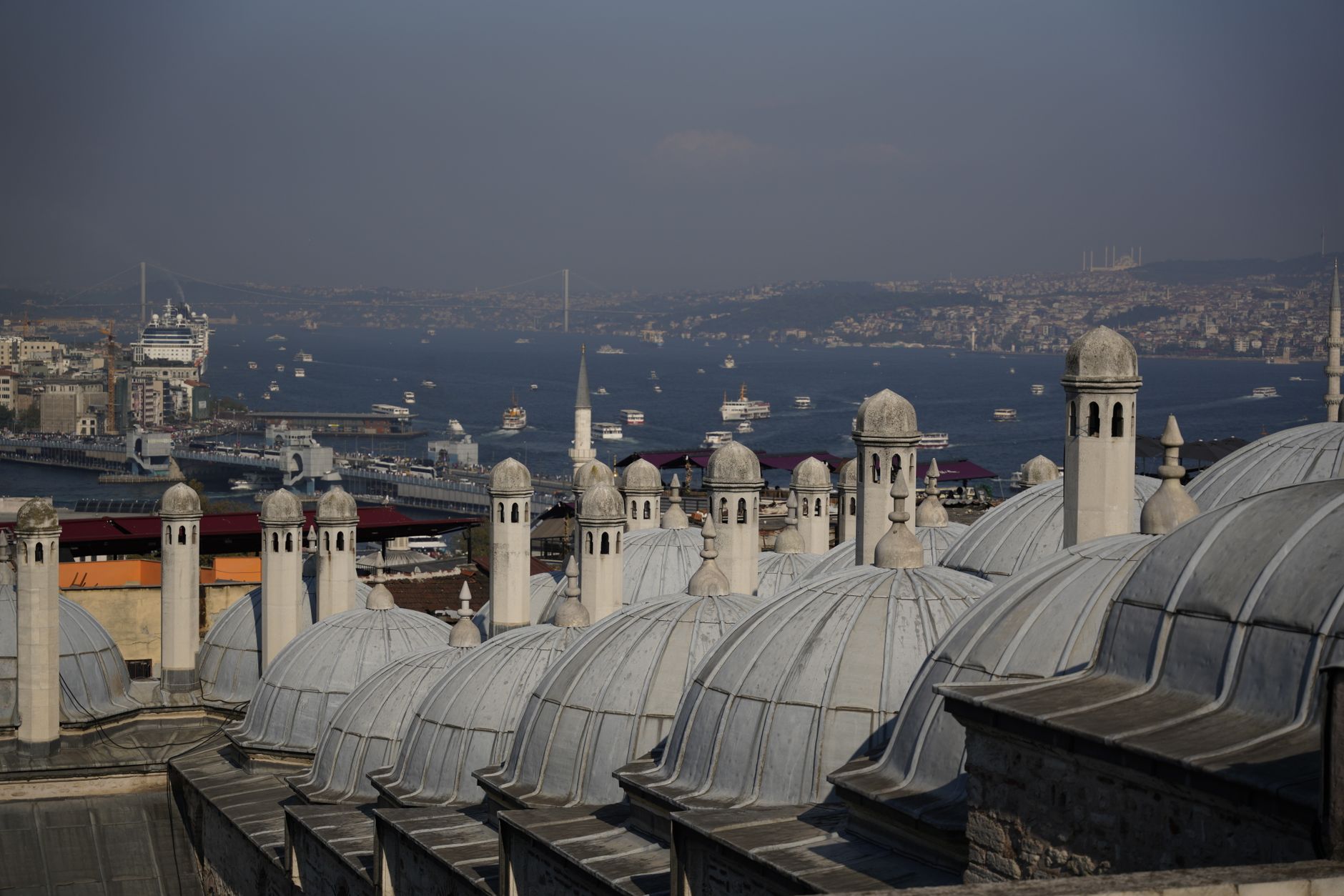 Panoramic view of Istanbul's Bosphorus with domed roofs in foreground.