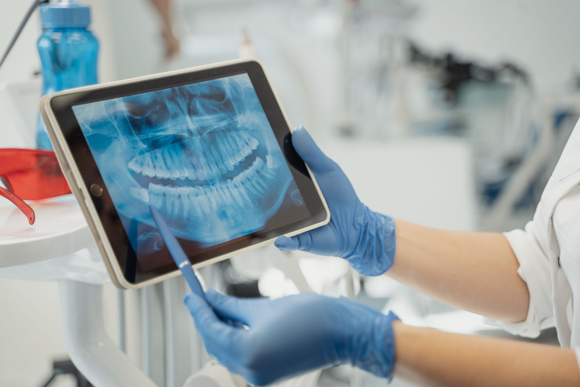 Dentist holding a tablet displaying an X-ray image in a dental clinic.