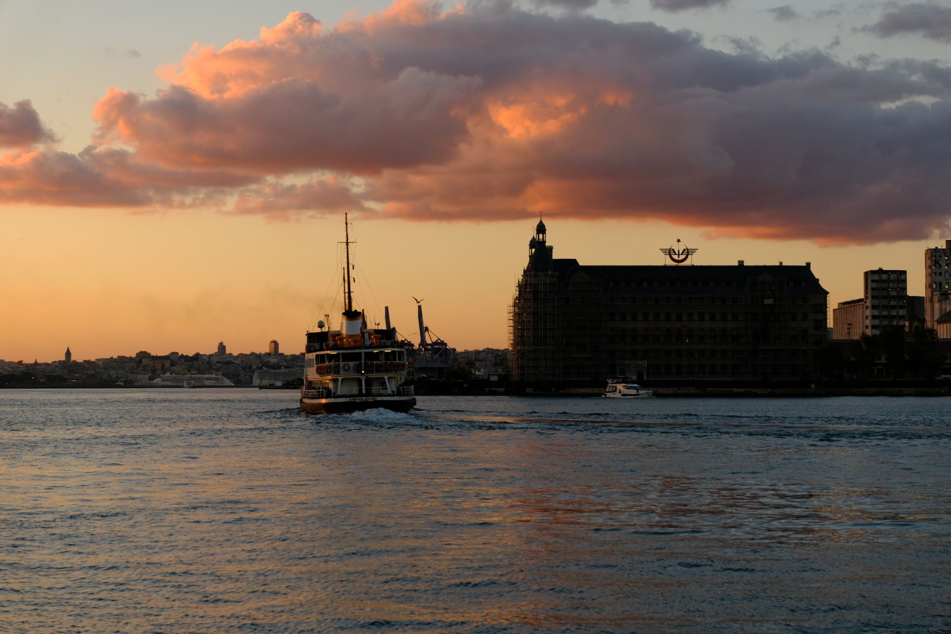 Istanbul's Asian side at sunset, featuring a boat and historic buildings.