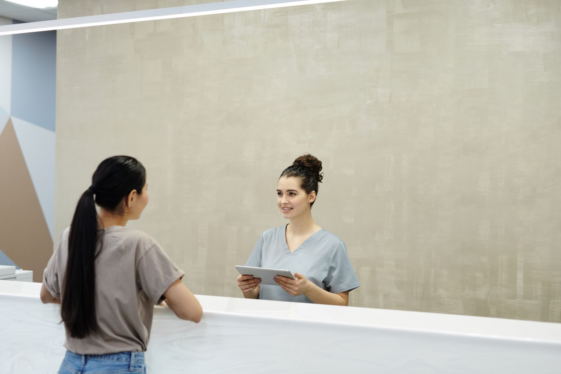A smiling coordinator assists a patient at the clinic reception, showcasing a welcoming atmosphere.