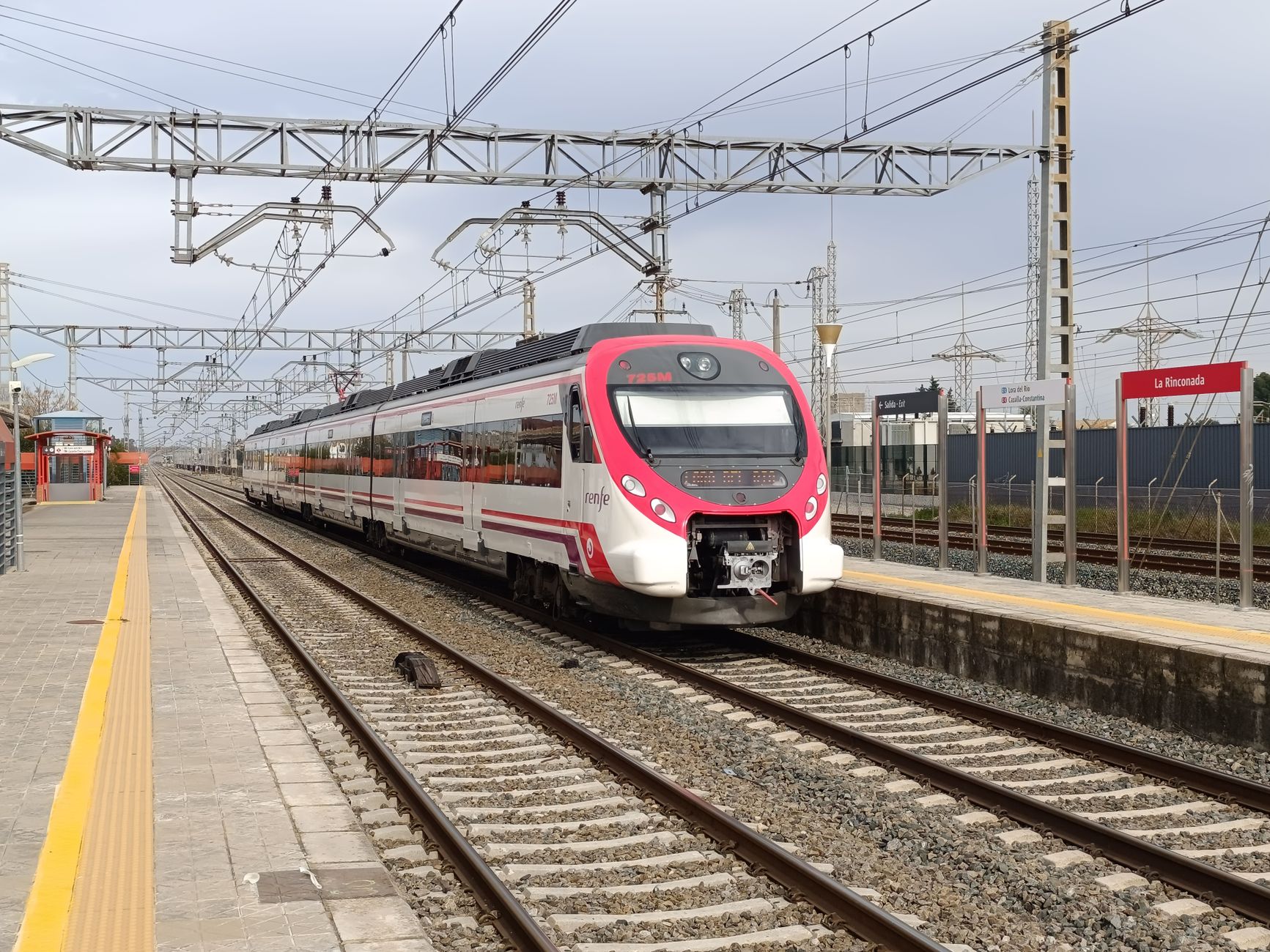A modern Renfe train arrives at La Rinconada station, showcasing efficient transport access.