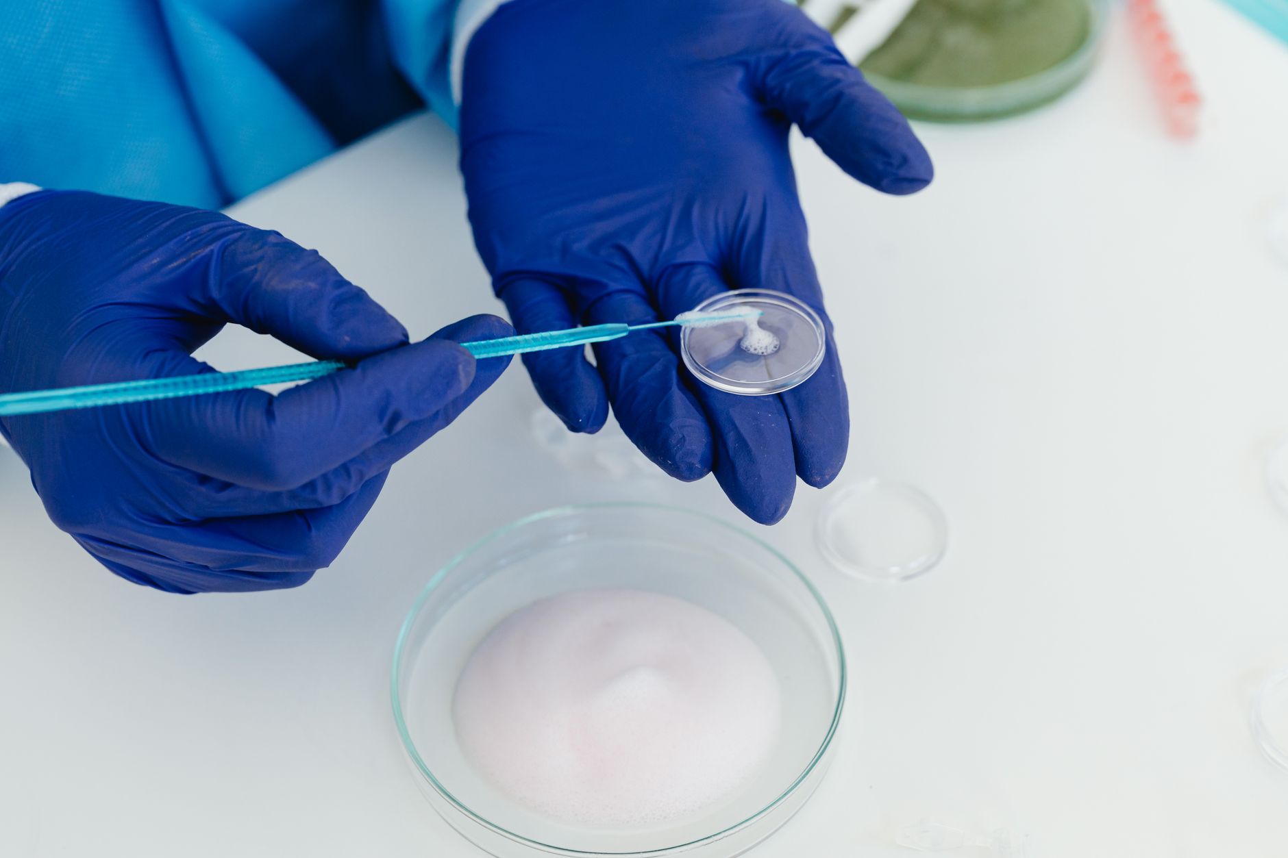 A lab technician performs ICSI procedure with microtools and a petri dish.