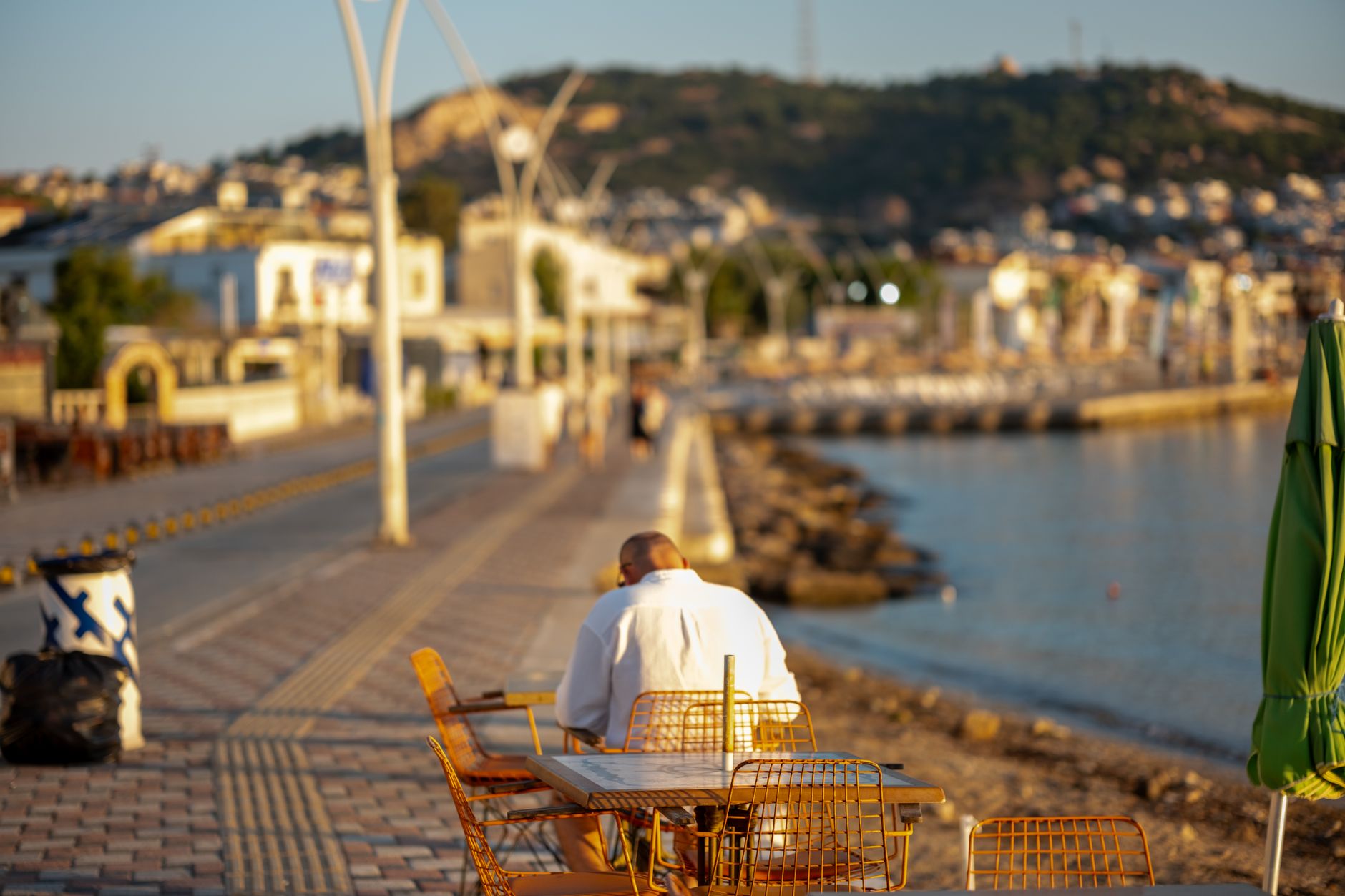 A peaceful seaside view in İzmit with a man sitting at a cafe table.