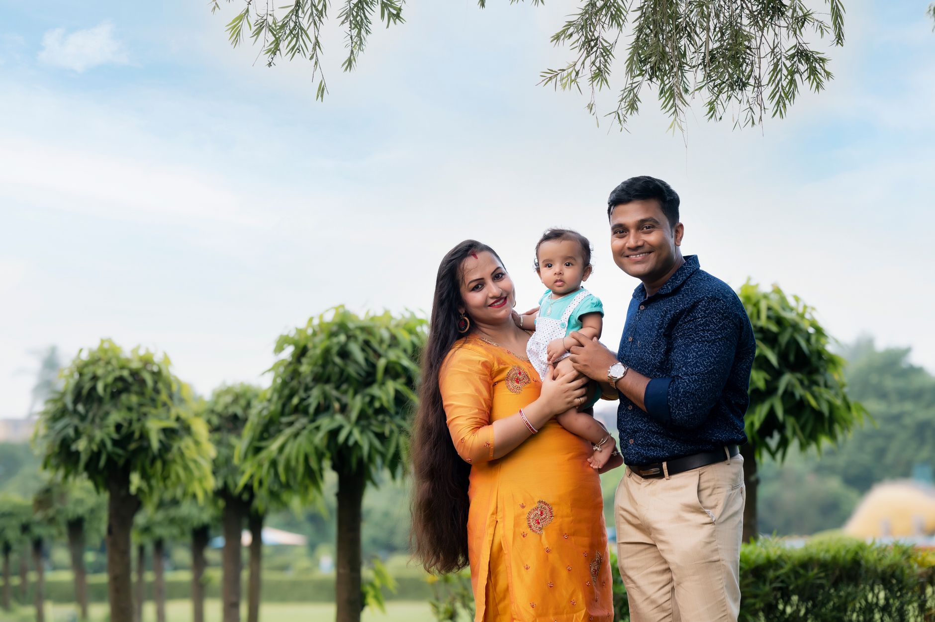 A happy couple poses with their baby outdoors, celebrating parenthood after IVF treatment.