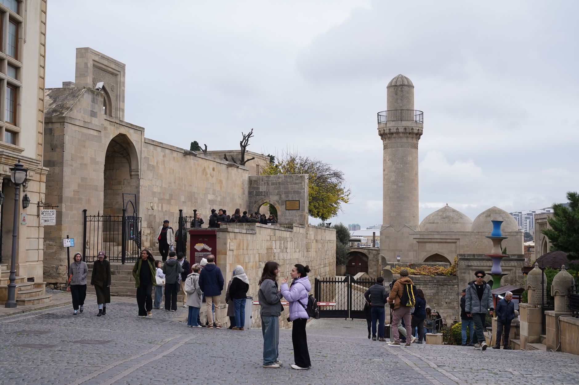 Visitors explore Gaziantep Castle, surrounded by historic architecture and cloudy skies.