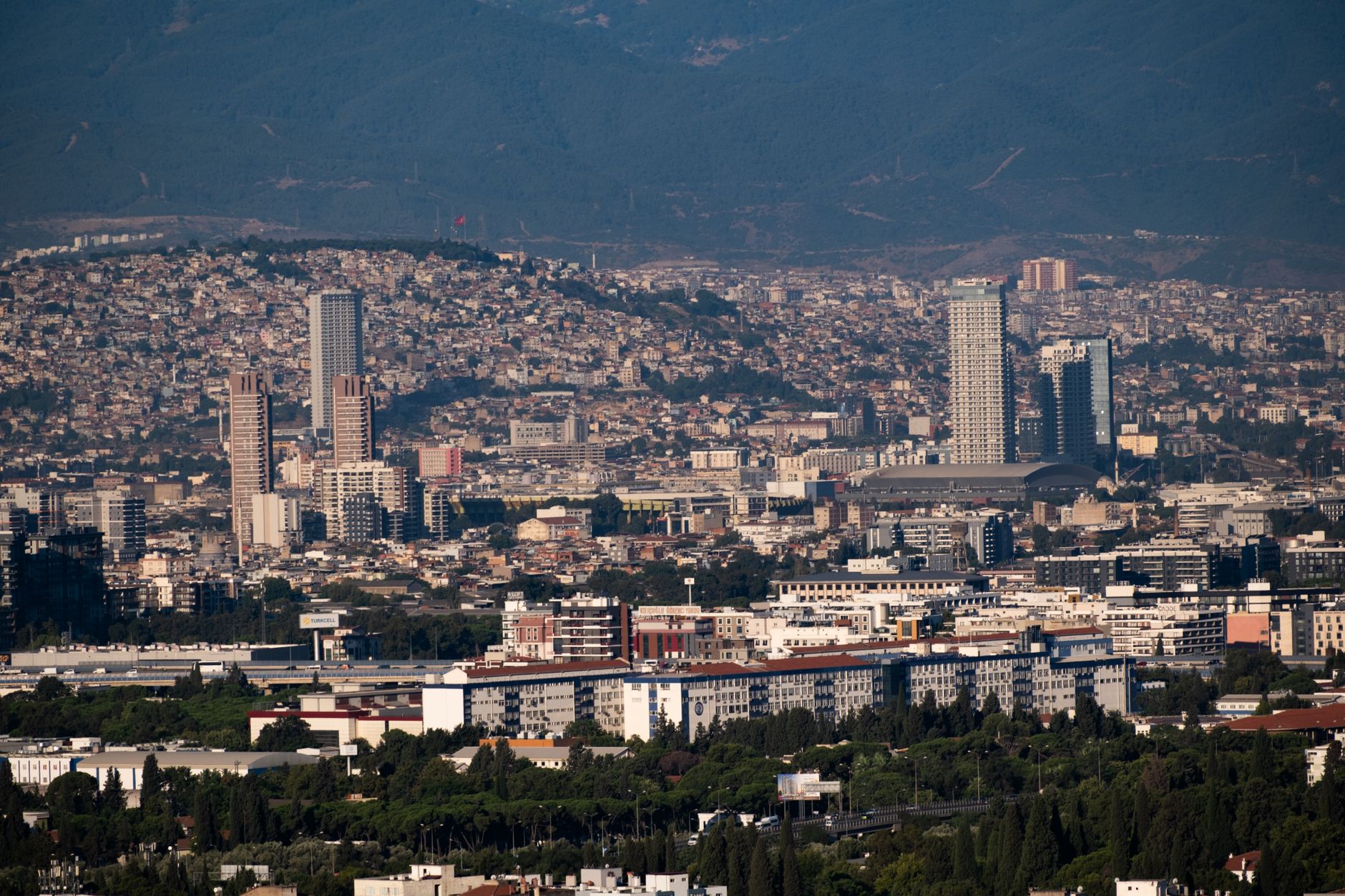 Aerial view of Izmir showcasing a coastal cityscape with mountains and urban structures.