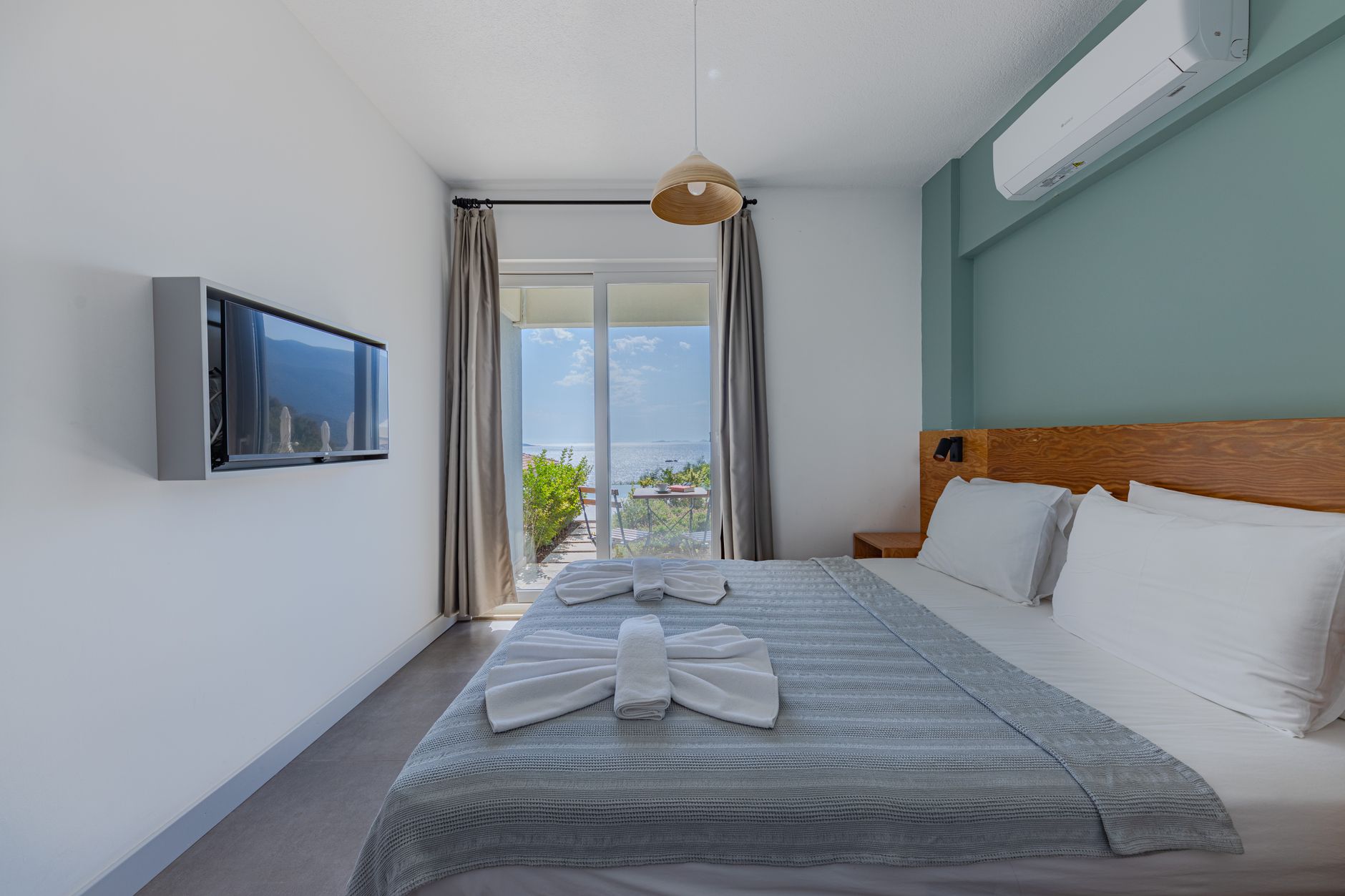 Spacious recovery room featuring a bed, TV, and sea view through large windows.