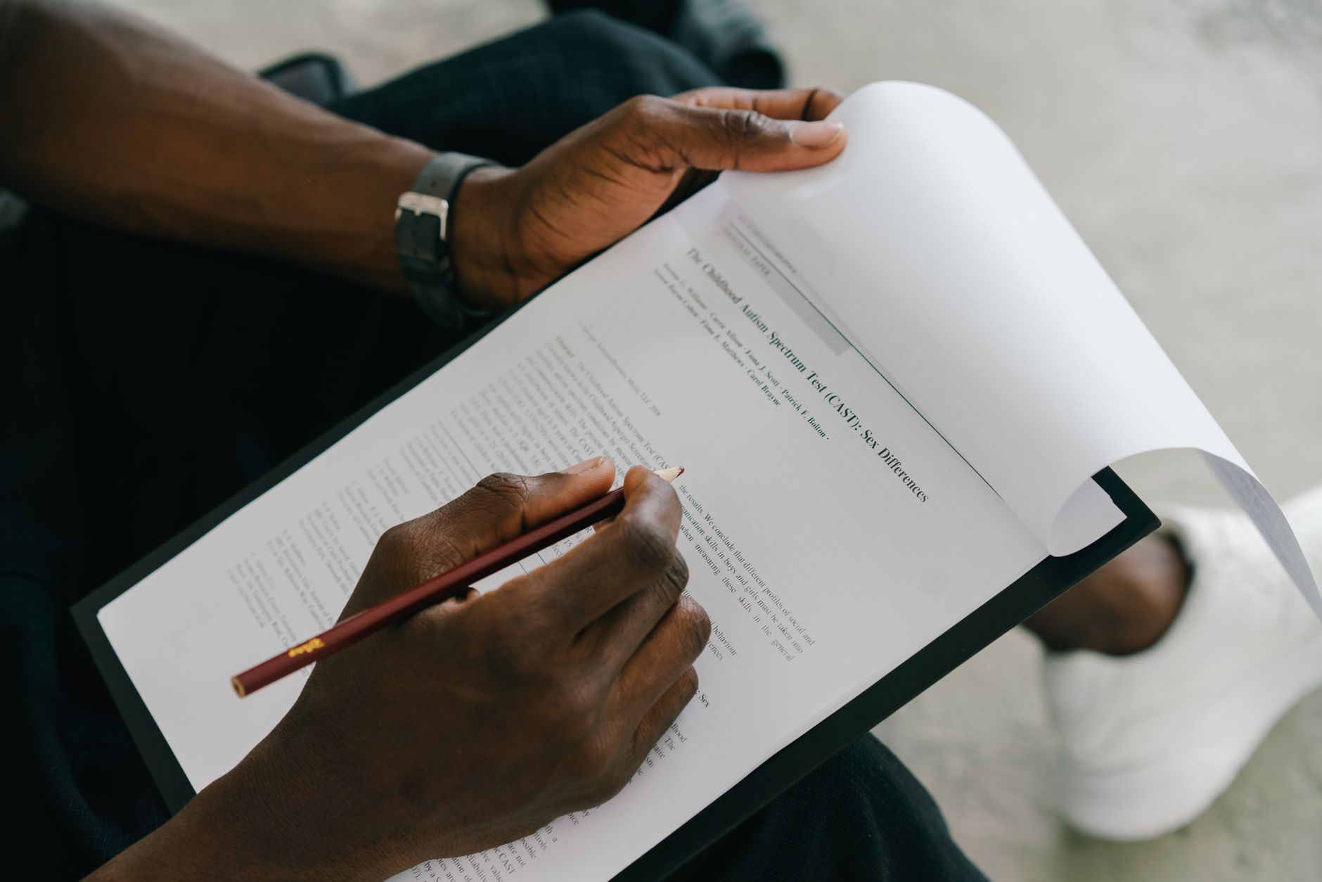 Close-up of hands holding a research paper and pencil, reviewing material.