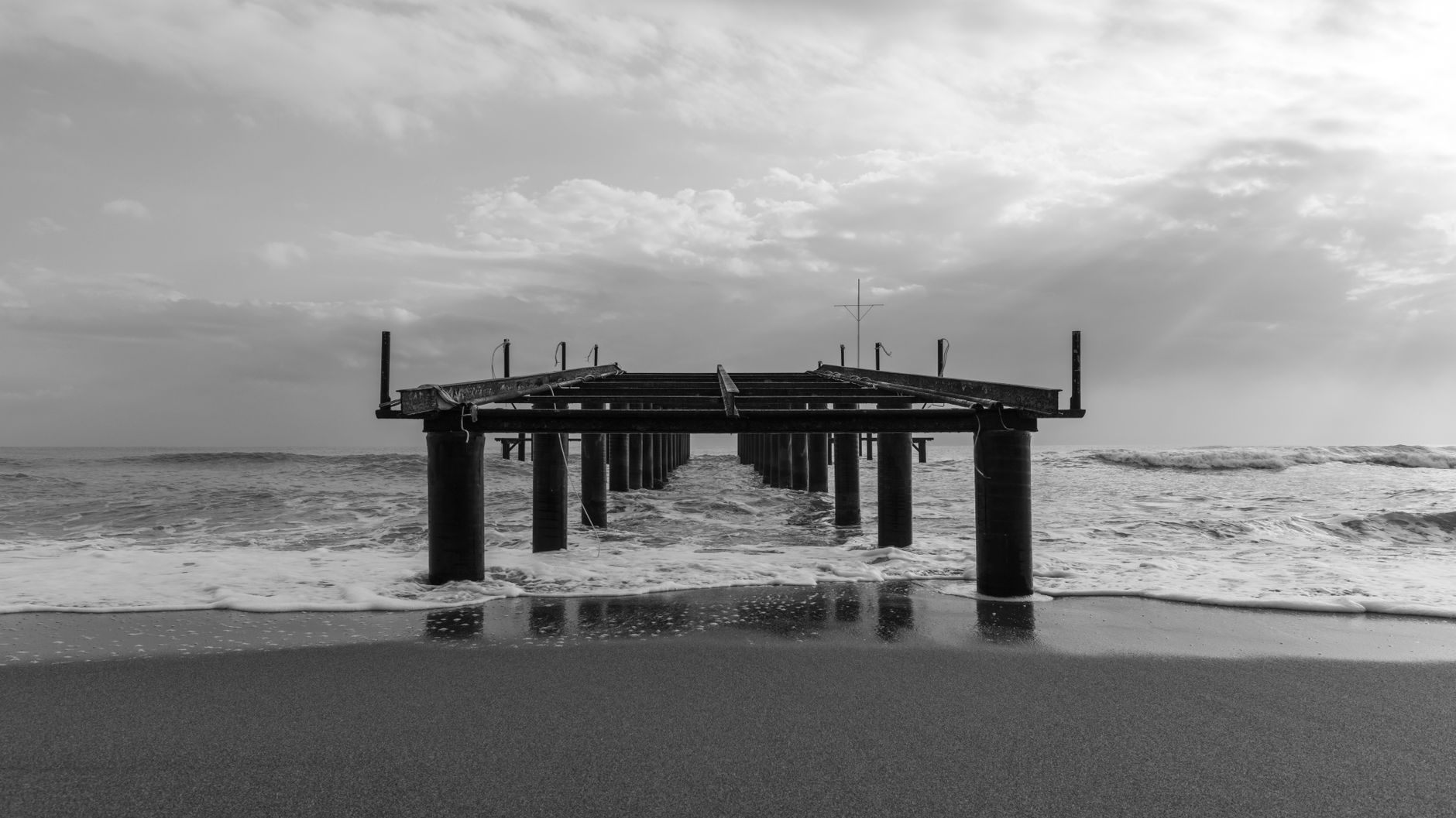 伊内阿达海滩上伸入海中的栈桥，海浪与云层相伴。