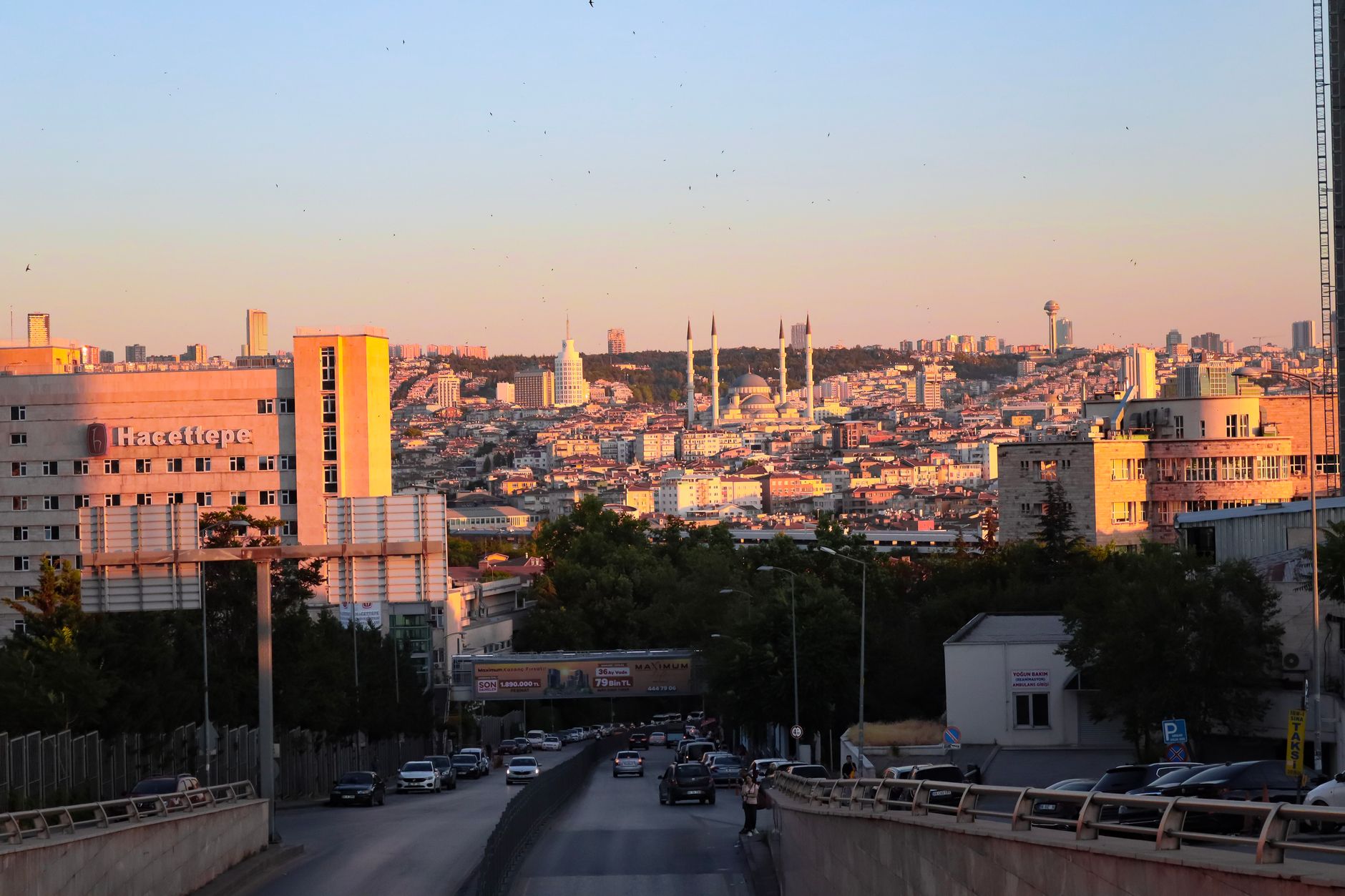 A scenic view of Hacettepe University Hospital and Ankara skyline during sunset, showcasing city lights.