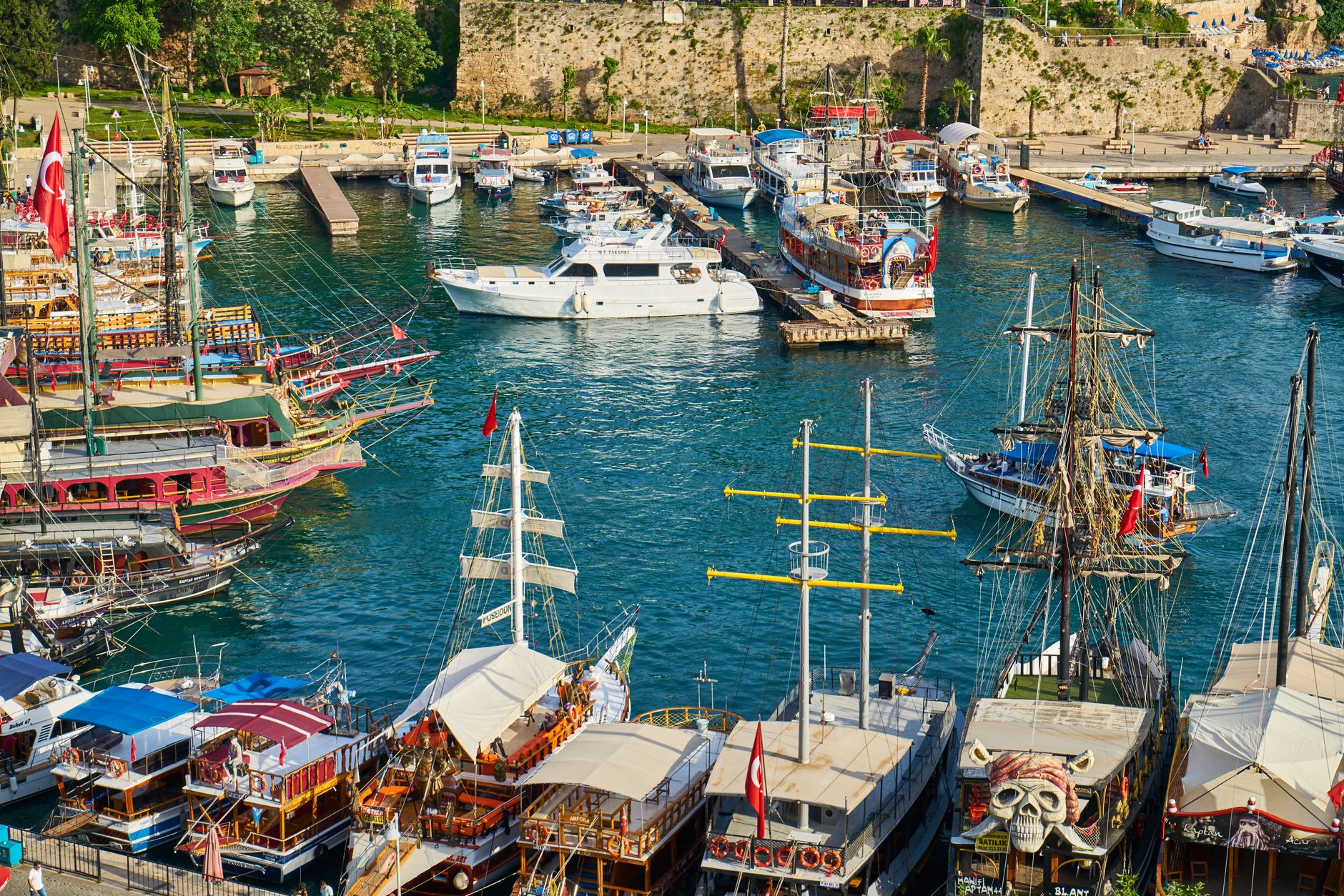 Vibrant boats moored in Antalya's old town harbour, surrounded by stunning scenery.