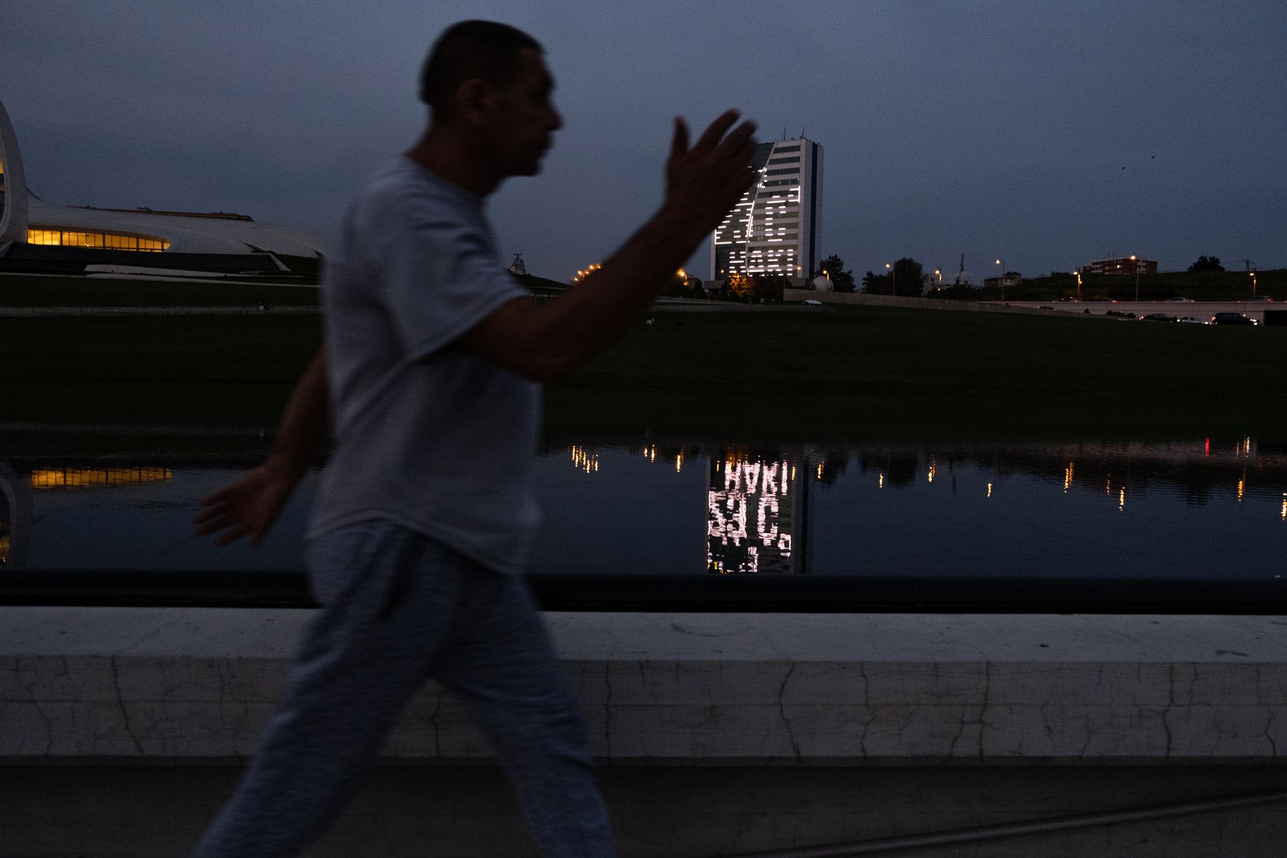 A person walking with assistance along a park pathway at twilight.