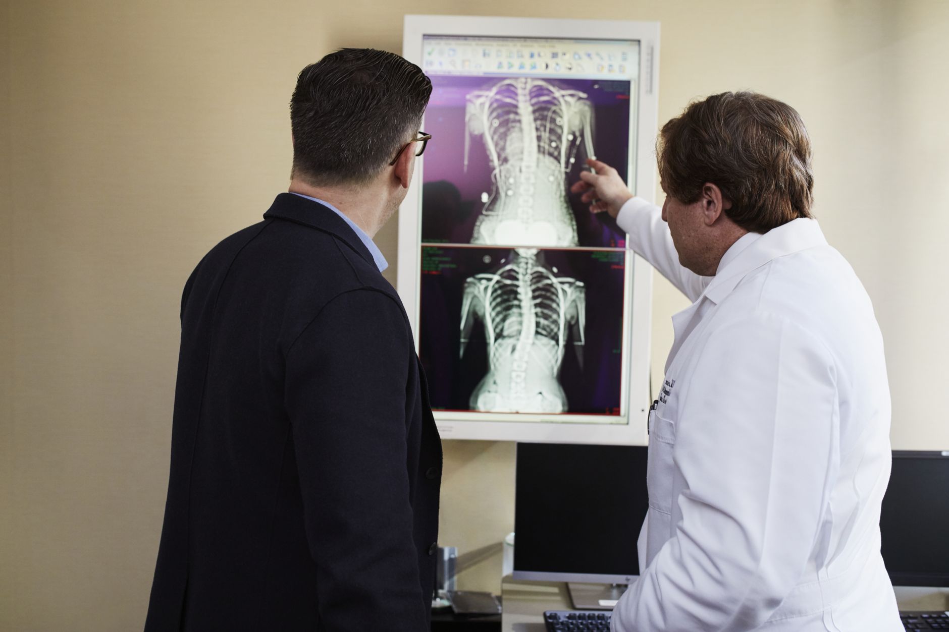 An orthopaedic surgeon points at X-ray results while consulting with a patient.