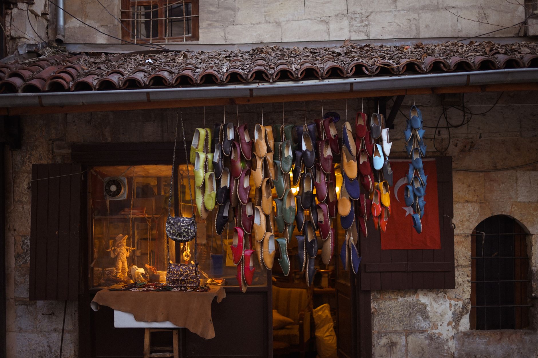 Vibrant market scene featuring an array of colorful shoes hanging outside a shop.