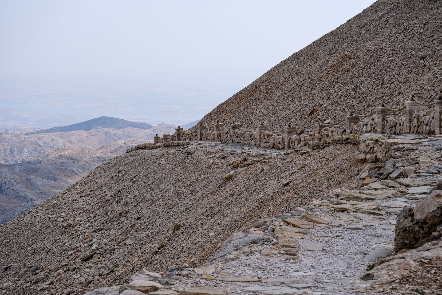 Walking trail winding through rocky terrain with distant views of Lake Bafa and surrounding hills.