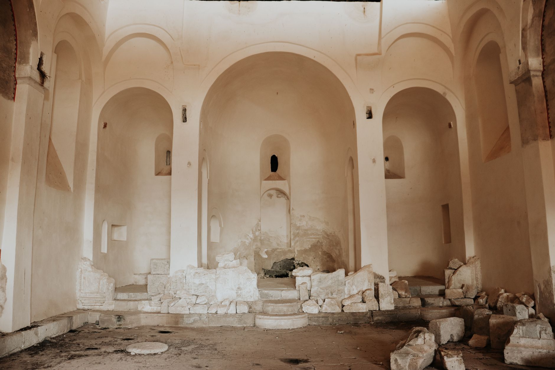 Interior view of the ruins of an early Christian church in Laodikeia, showcasing arched architecture and scattered stones.
