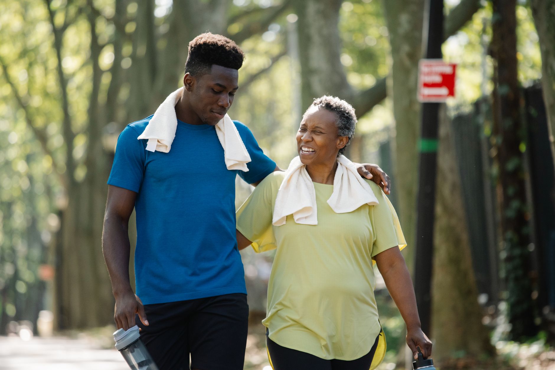 A senior man and woman walking together in a park, both smiling and active.