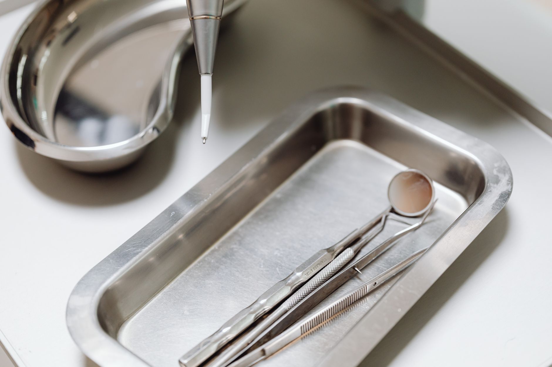 Metal surgical tray with dental instruments and laser tool ready for a procedure.