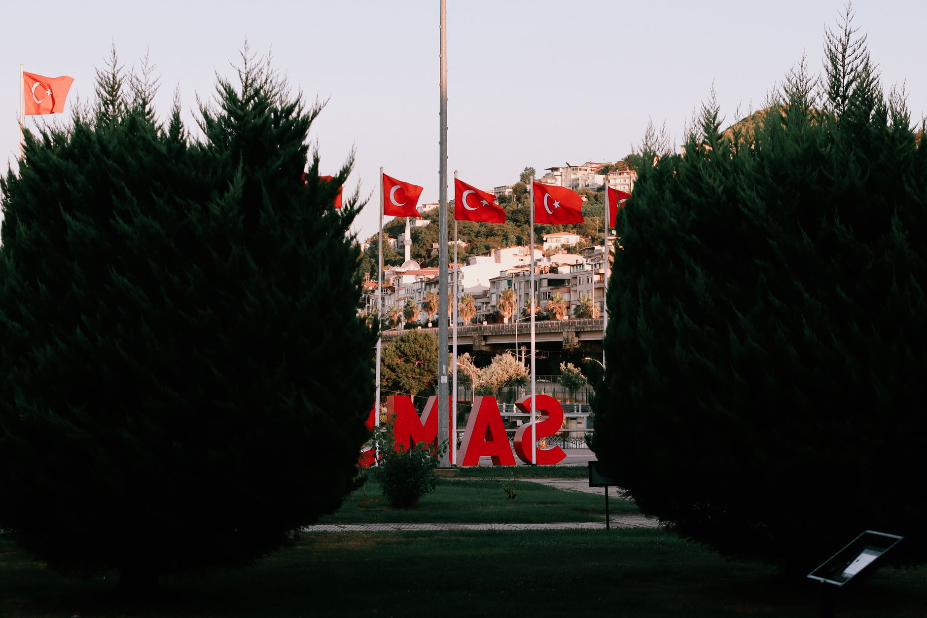 View of Batı Park in Samsun, featuring Turkish flags, greenery, and city buildings.