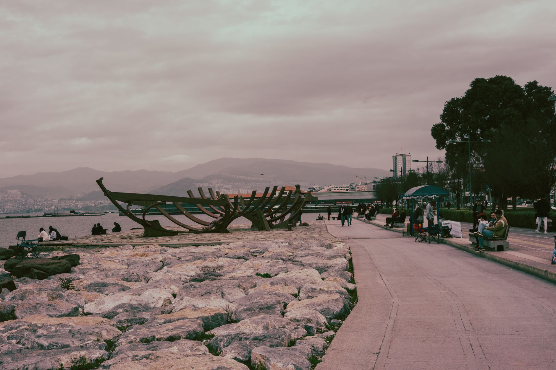 Serene view of Kordon promenade in Izmir with sculptures, benches, and people enjoying the waterfront.