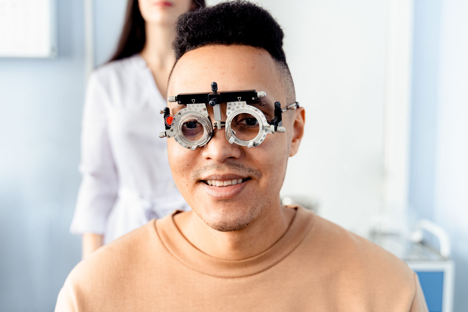 A joyful patient wearing vision test goggles, smiling with clear vision after LASIK.