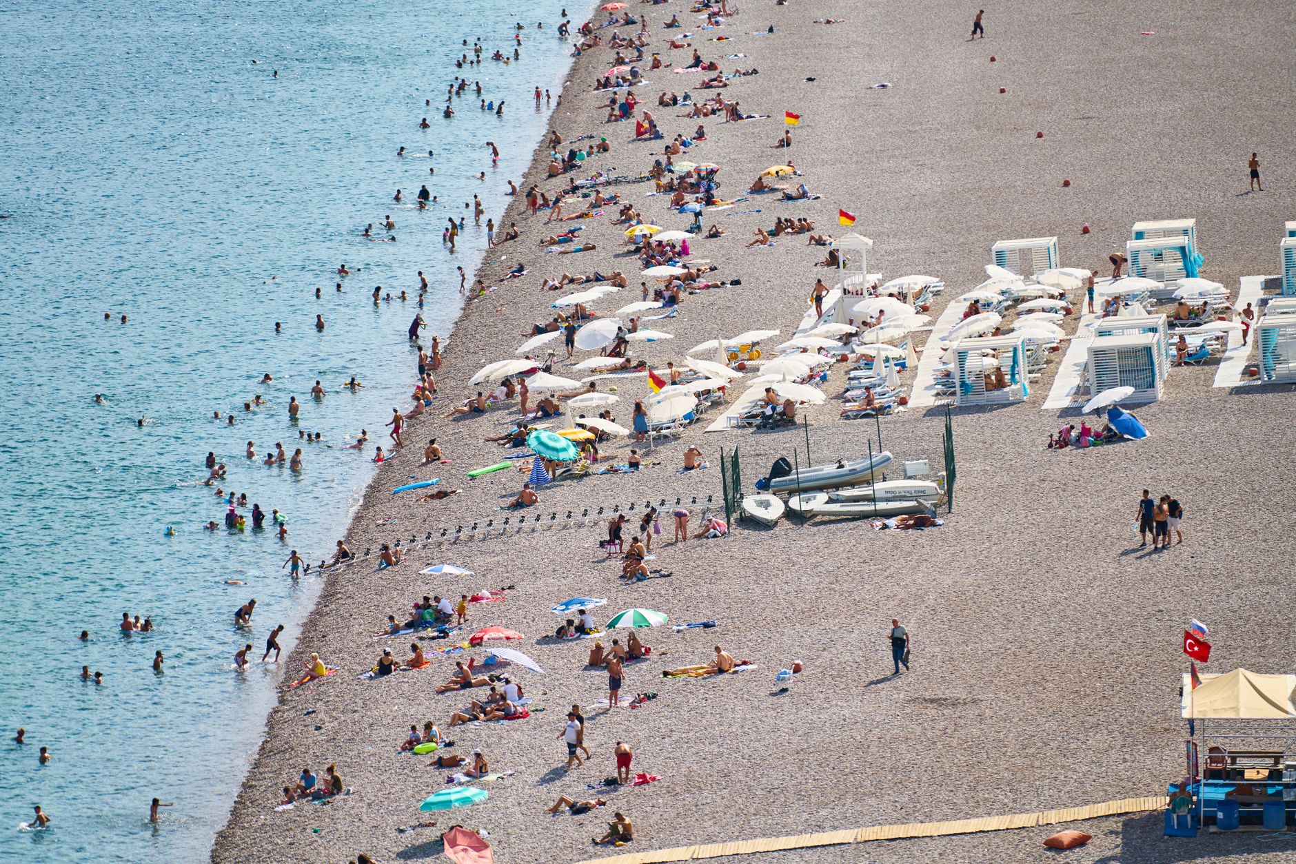 Antalya'da güneşin ve denizin tadını çıkaran ailelerle dolu kalabalık bir plaj tatil köyü.