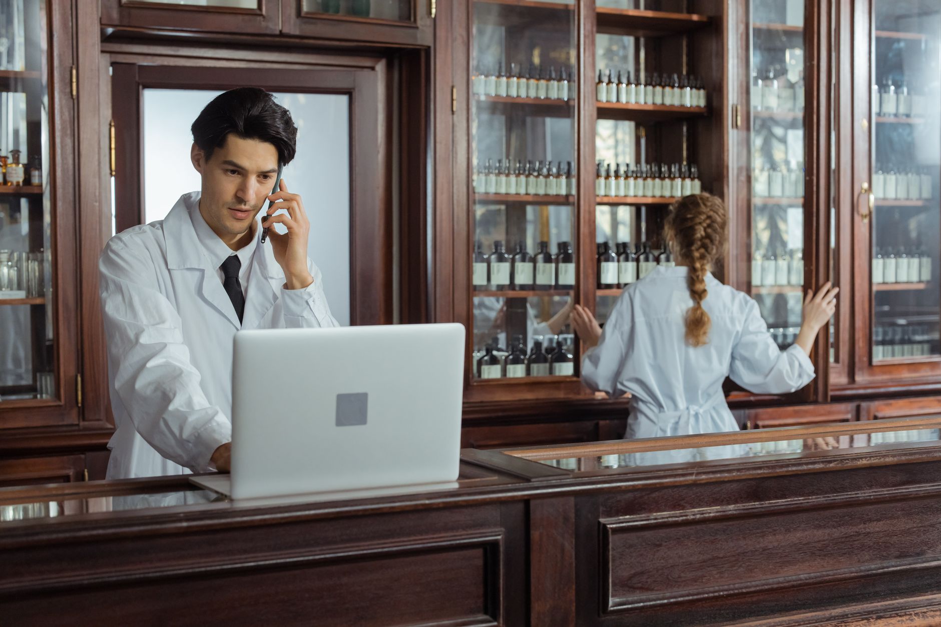 A pharmacist on the phone while working at a computer in a pharmacy.