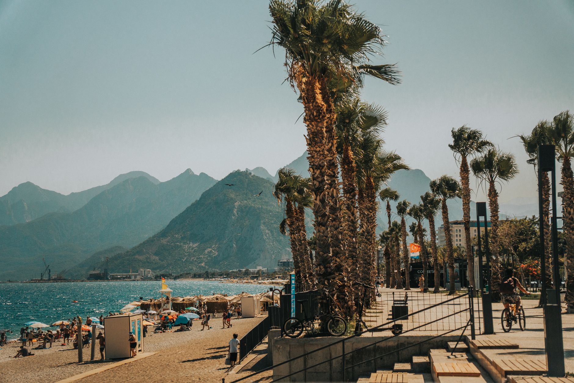 Patients participate in cardiac rehab while walking along a picturesque promenade in Antalya, surrounded by palm trees and mountains.