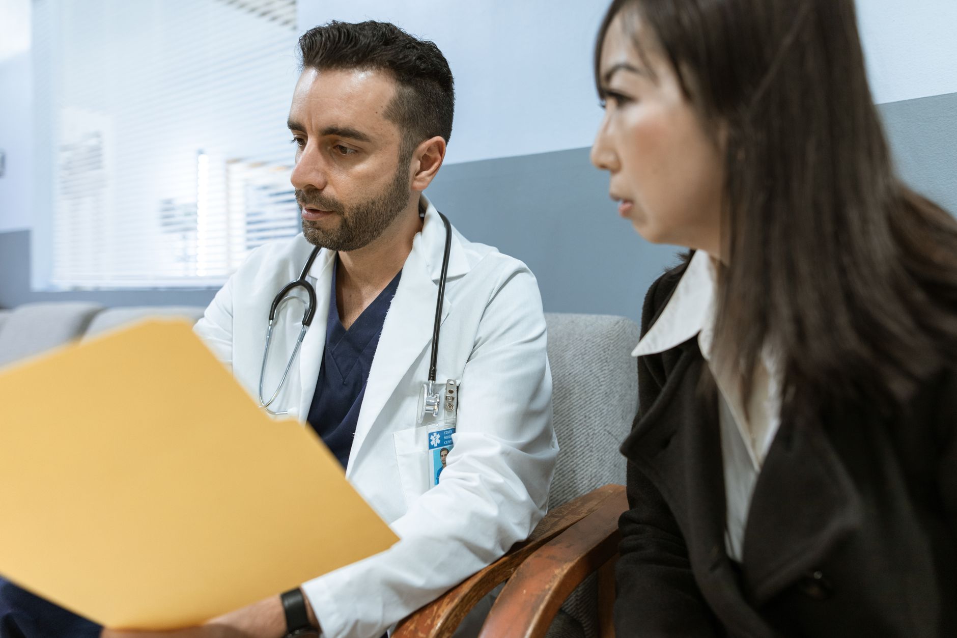 Doctor reviewing patient file with a woman in a hospital setting.