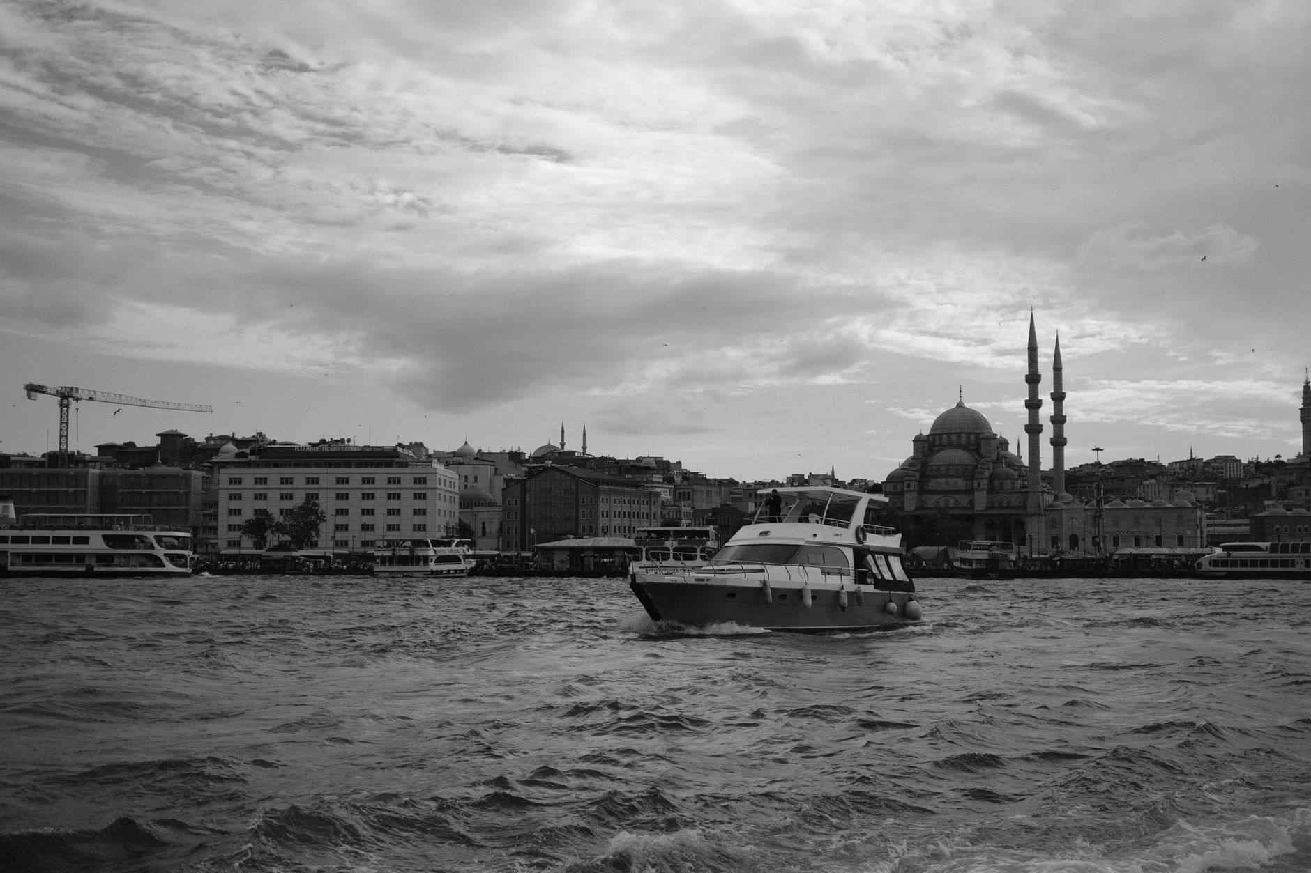 Black and white photo of Istanbul skyline with a boat on the Bosphorus.