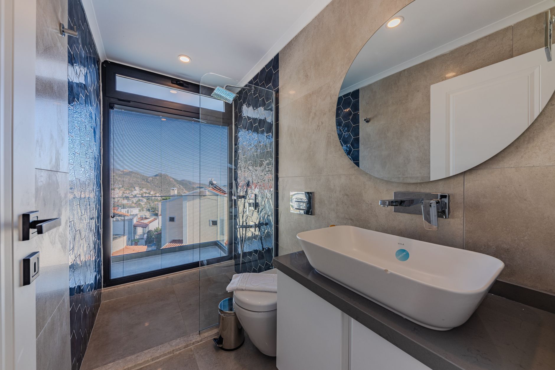 Modern bathroom with roll-in shower and city view, featuring grab bars.