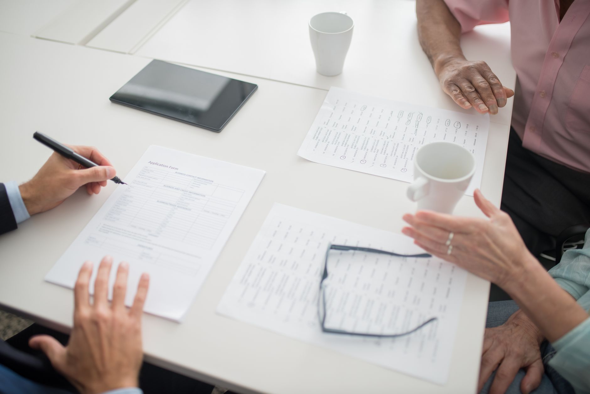 Individuals discussing insurance documents and quotes at a desk.