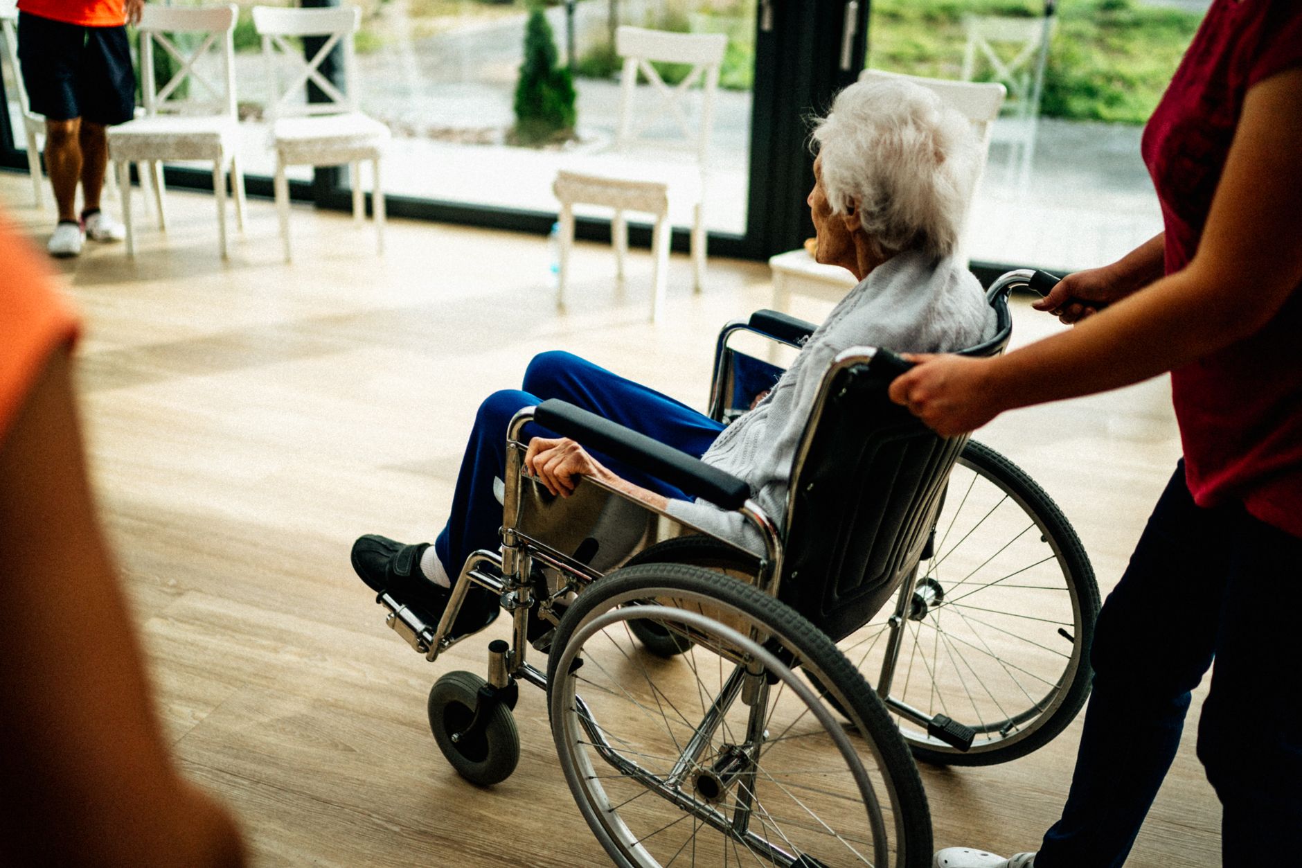 A nurse helps an elderly woman in a wheelchair, showcasing attentive nursing care.