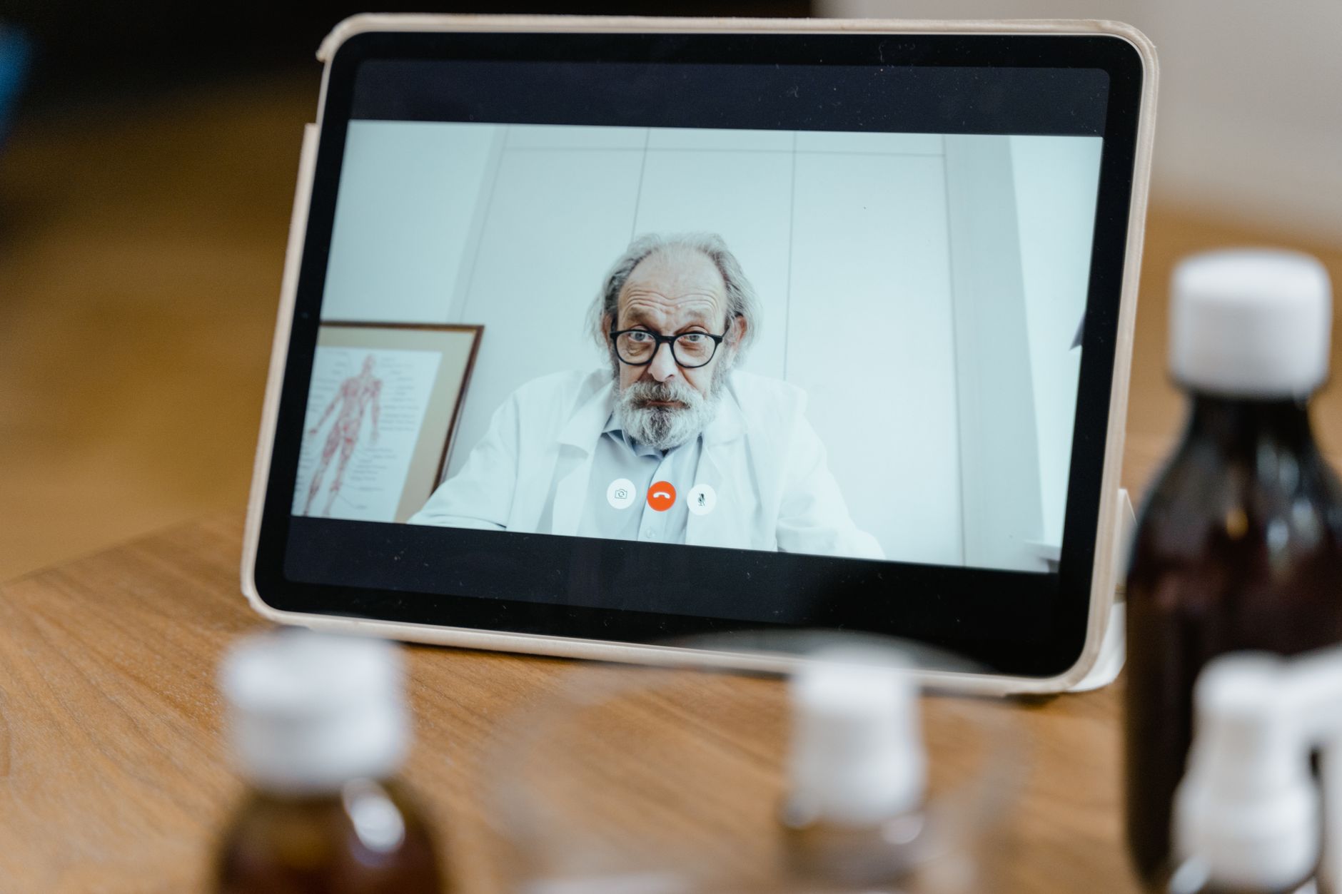A doctor in a lab coat conducting a video consultation on a tablet.