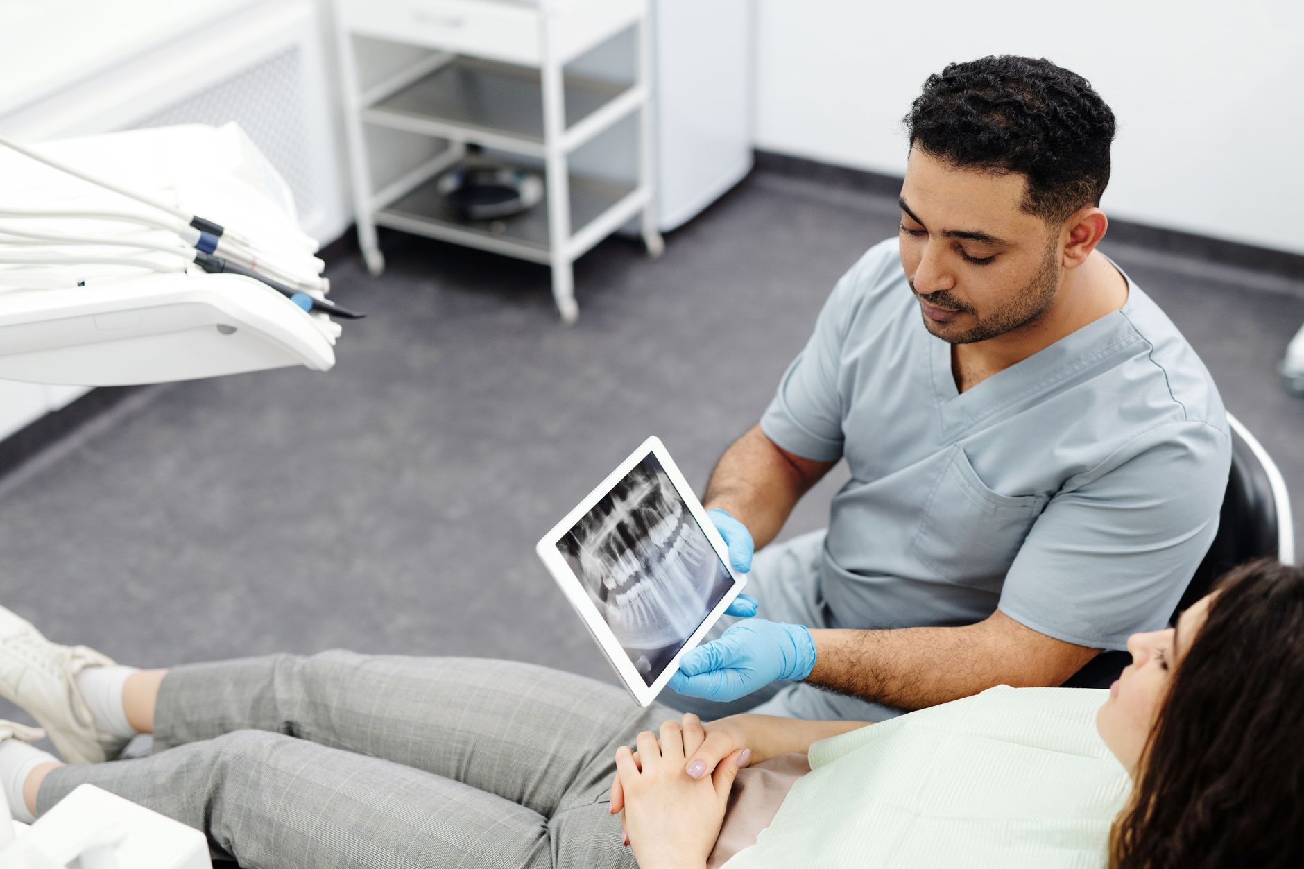 Dentist showing dental X-ray on a tablet to patient during consultation.
