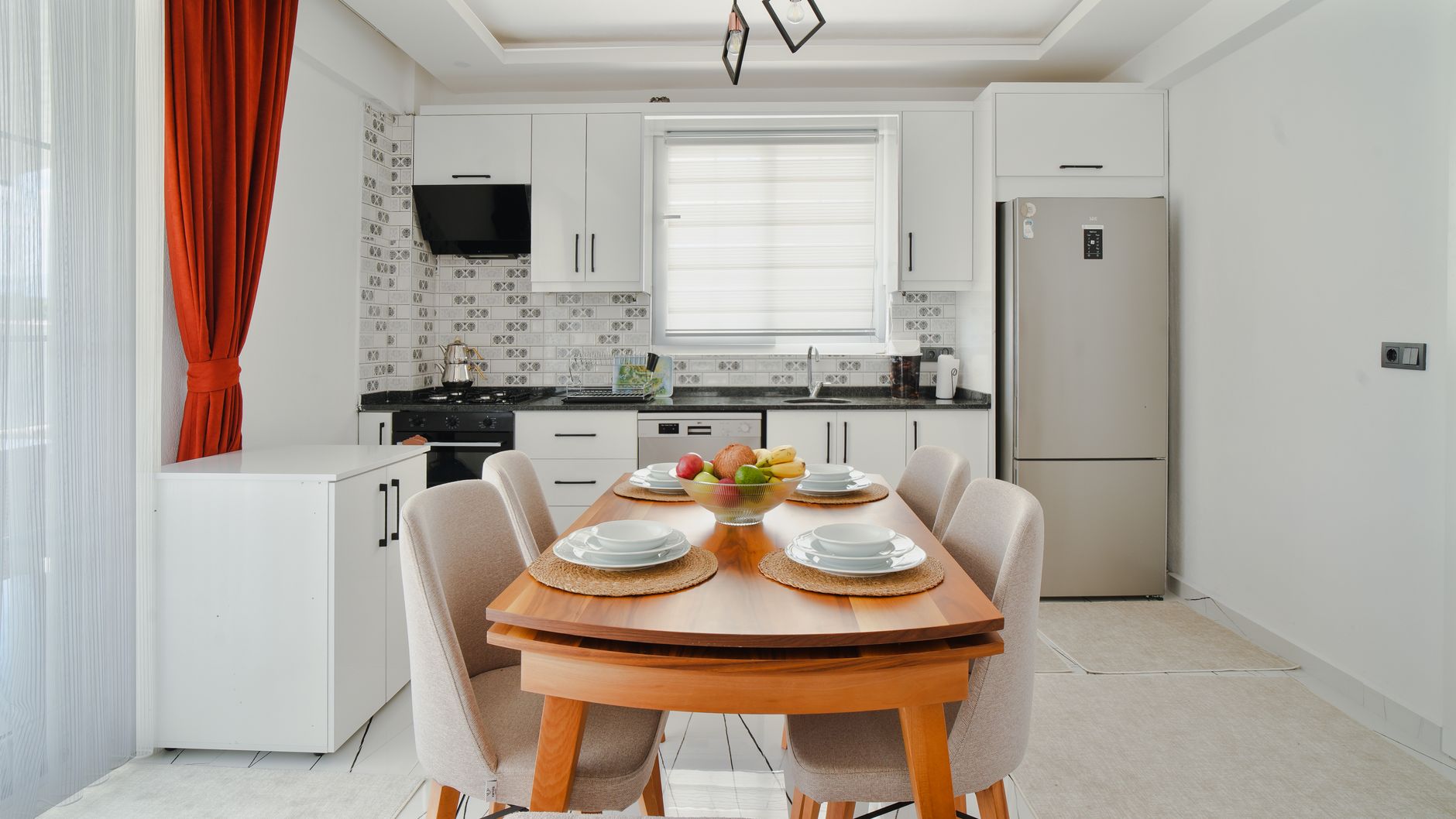 Modern kitchen in a bright family apartment with a dining table, fruit bowl, and elegant decor.