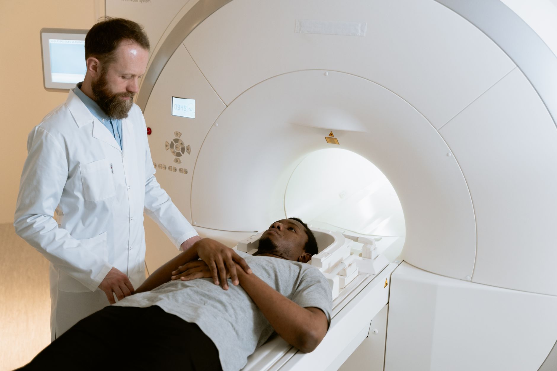 A patient lies on an MRI machine while a doctor prepares for the scan.
