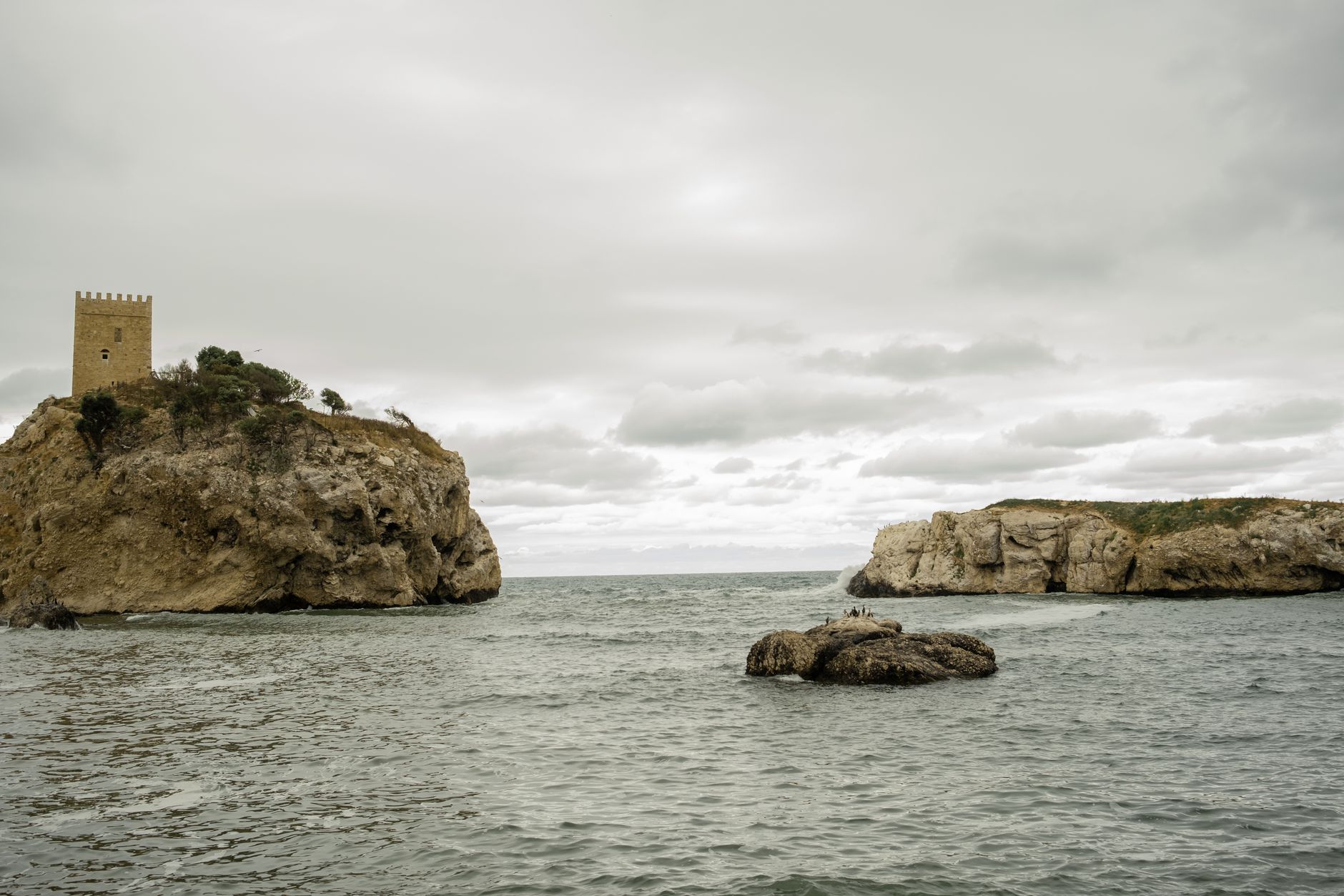 Calm sea view featuring a rocky coast and a historic tower near Istanbul.