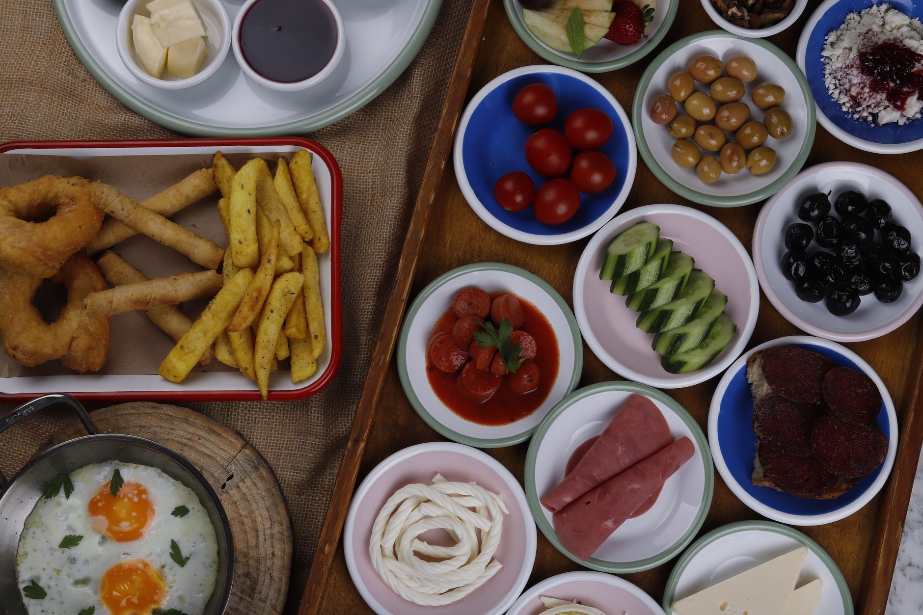 A diverse Turkish breakfast spread featuring olives, tomatoes, cucumbers, eggs, and various breads.