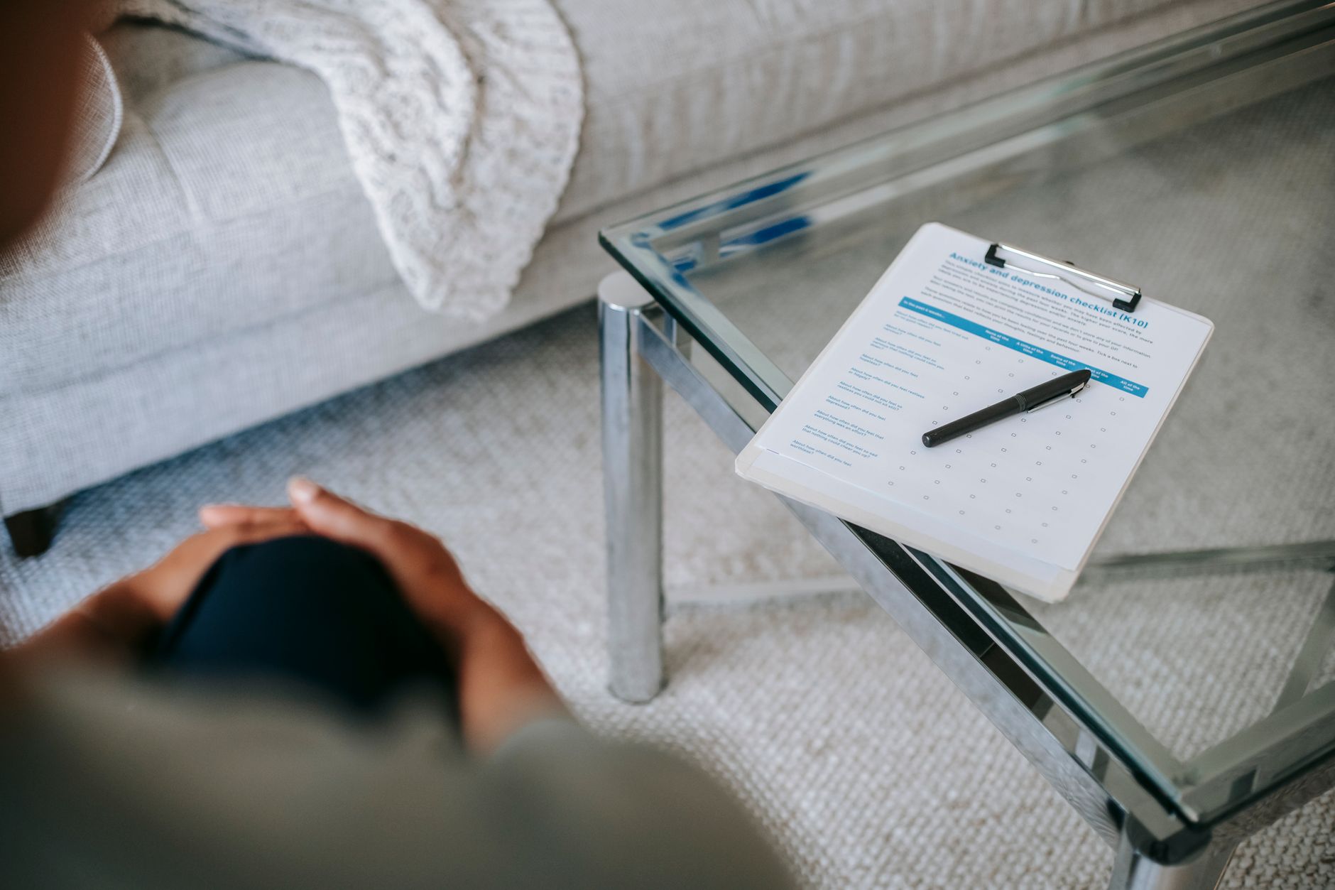 Close-up of a clipboard with anxiety and depression checklist, patient sitting nearby.