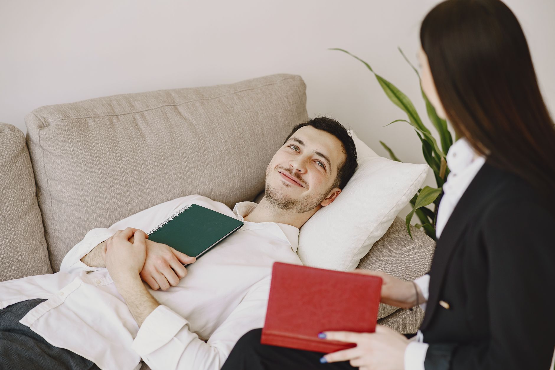 A man relaxes on a couch during a therapy session, engaging with a therapist.