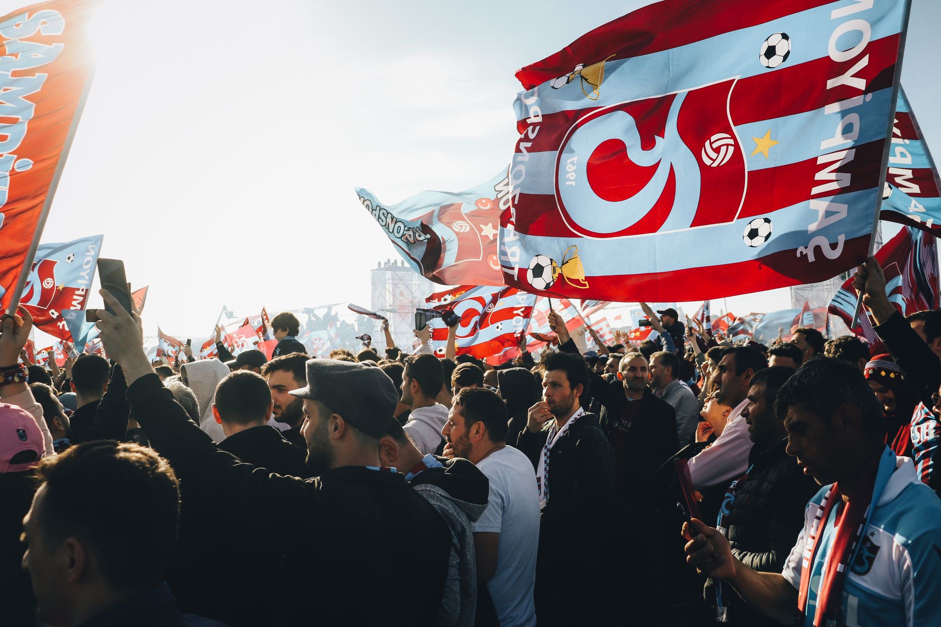 A crowd of passionate Trabzonspor supporters waving flags, creating a vibrant atmosphere during a match.