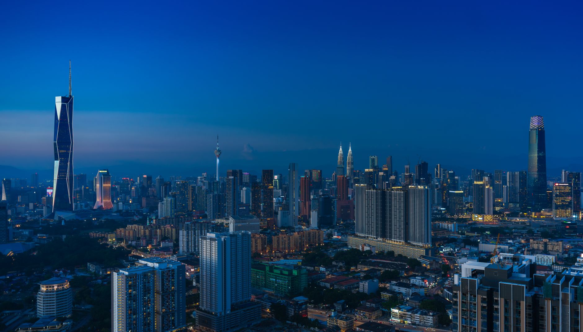 A panoramic view of Kuala Lumpur's skyline at dusk featuring iconic skyscrapers and vibrant city lights.