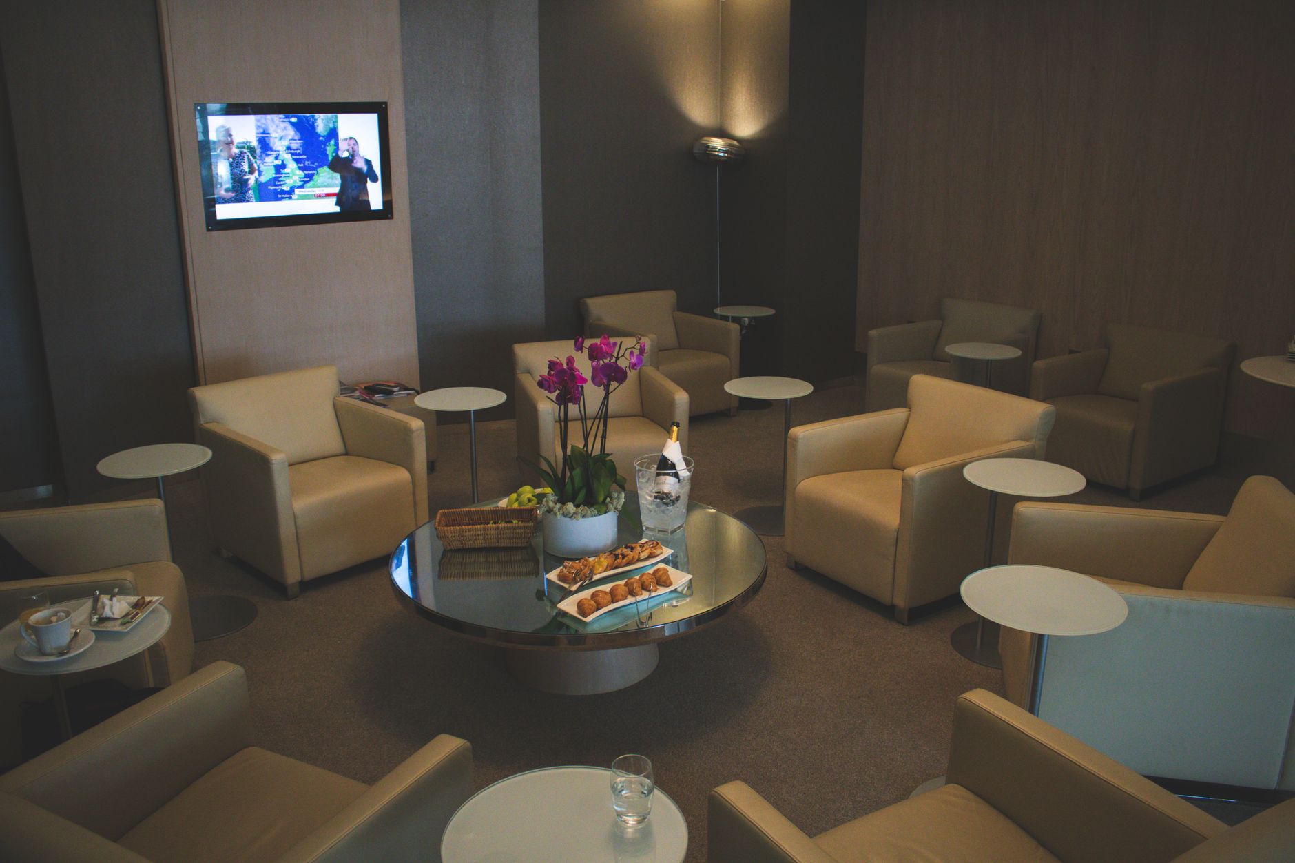 Calm airport lounge with comfortable chairs, snacks, and TV, ideal for waiting.
