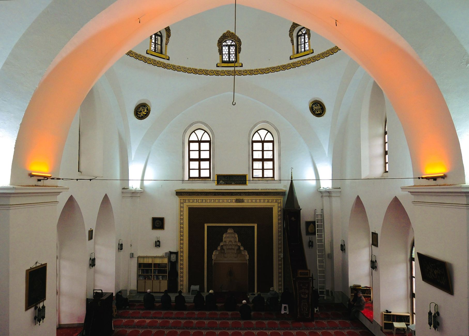 A view of the interior of a historic mosque in Bursa, showcasing arches, decorative elements, and worshippers.