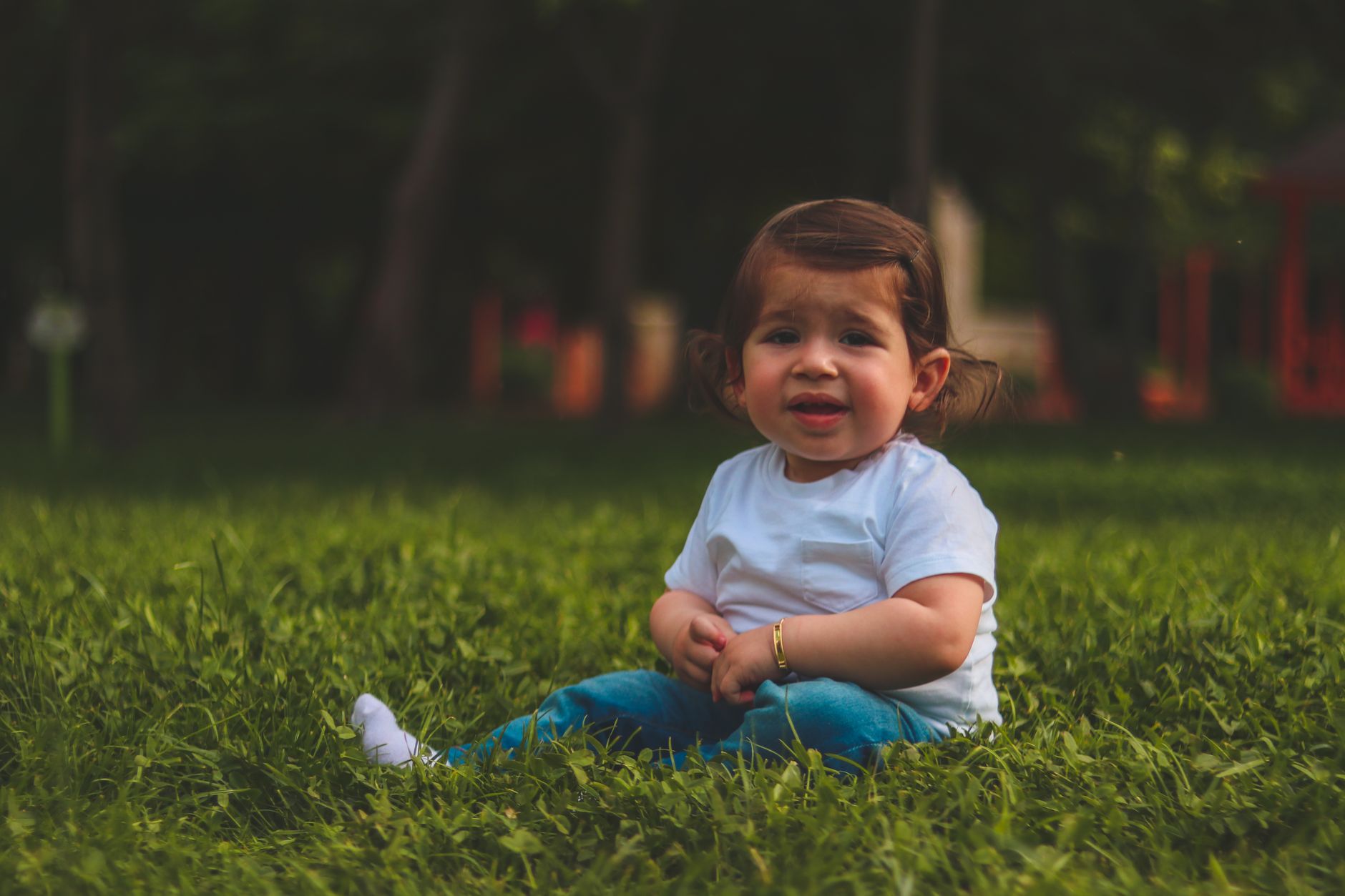 A joyful child sits on the grass in a hospital garden in Türkiye, symbolizing recovery and health.