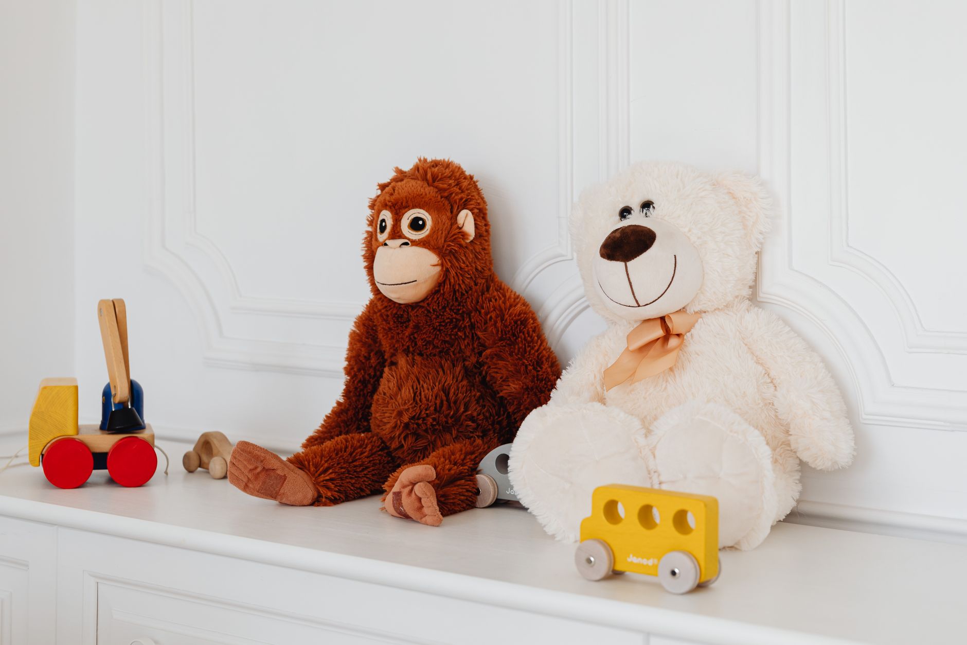 A cozy hospital playroom featuring a stuffed monkey, teddy bear, and colorful wooden toys.