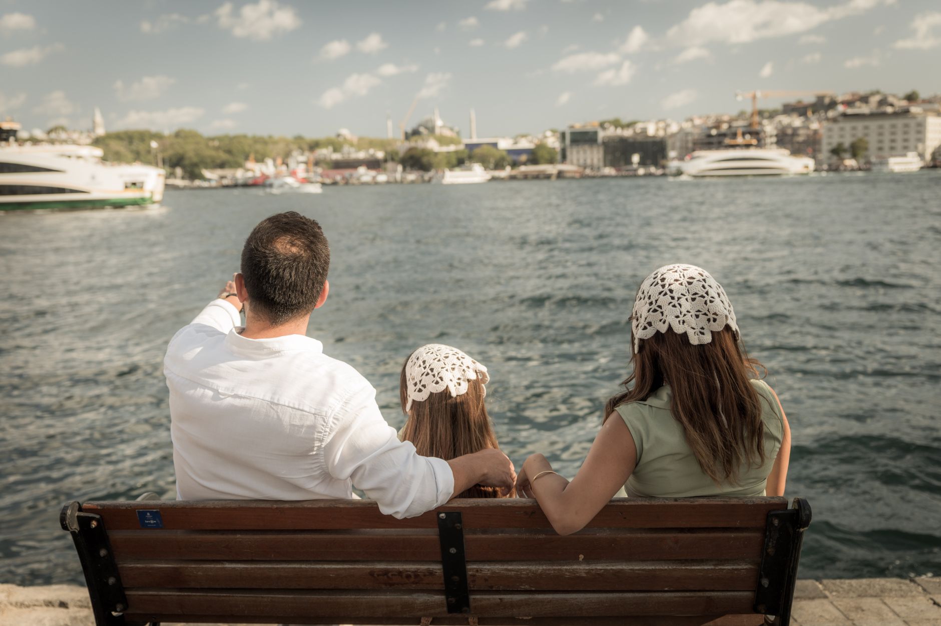 A family sitting on a bench by the Bosphorus, admiring Istanbul's skyline, symbolizing hope and togetherness.